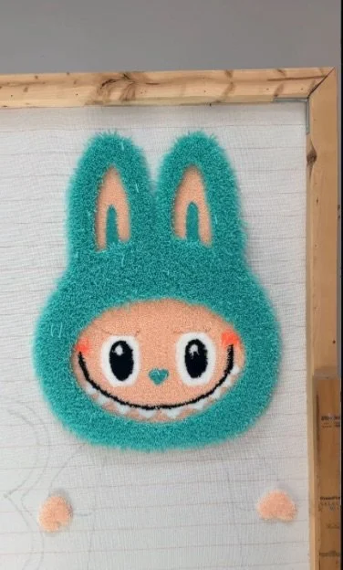 Fluffy bunny-shaped wall decoration with a smiling face, large eyes, and bunny ears.