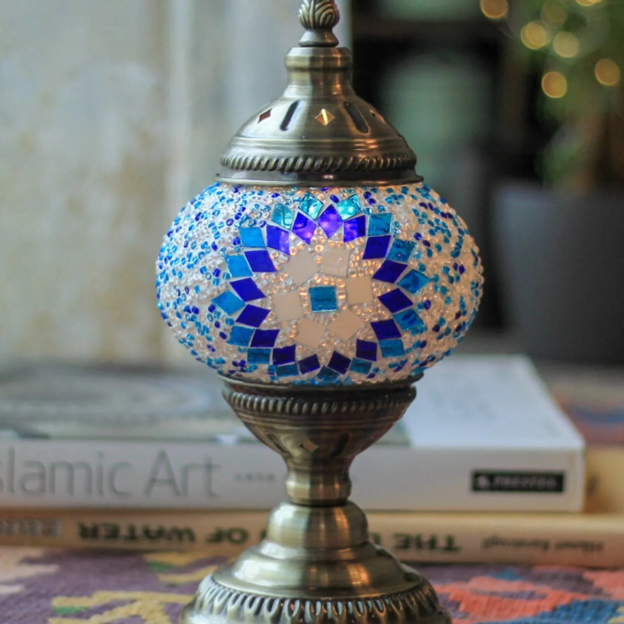 Mosaic lamp with blue and white glass pattern on a stack of books.
