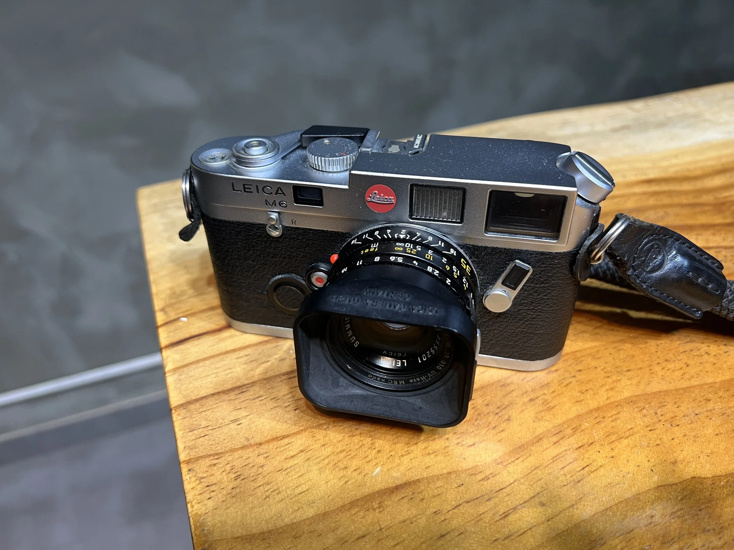 A Leica M6 rangefinder with a 35mm lens resting on a wooden bench.