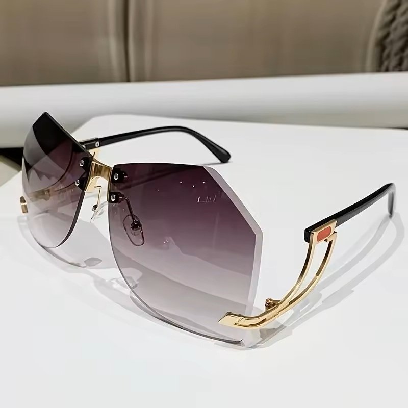 A pair of stylish sunglasses with gradient lenses and gold accented arms resting on a white surface.