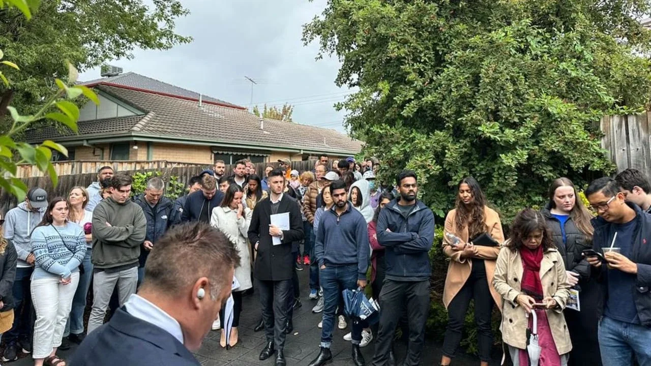 First-home buyers attending a crowded property auction in Melbourne, highlighting strong buyer demand