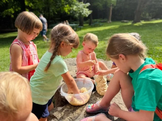 Group of young children playing with a dough mixture in the play area.