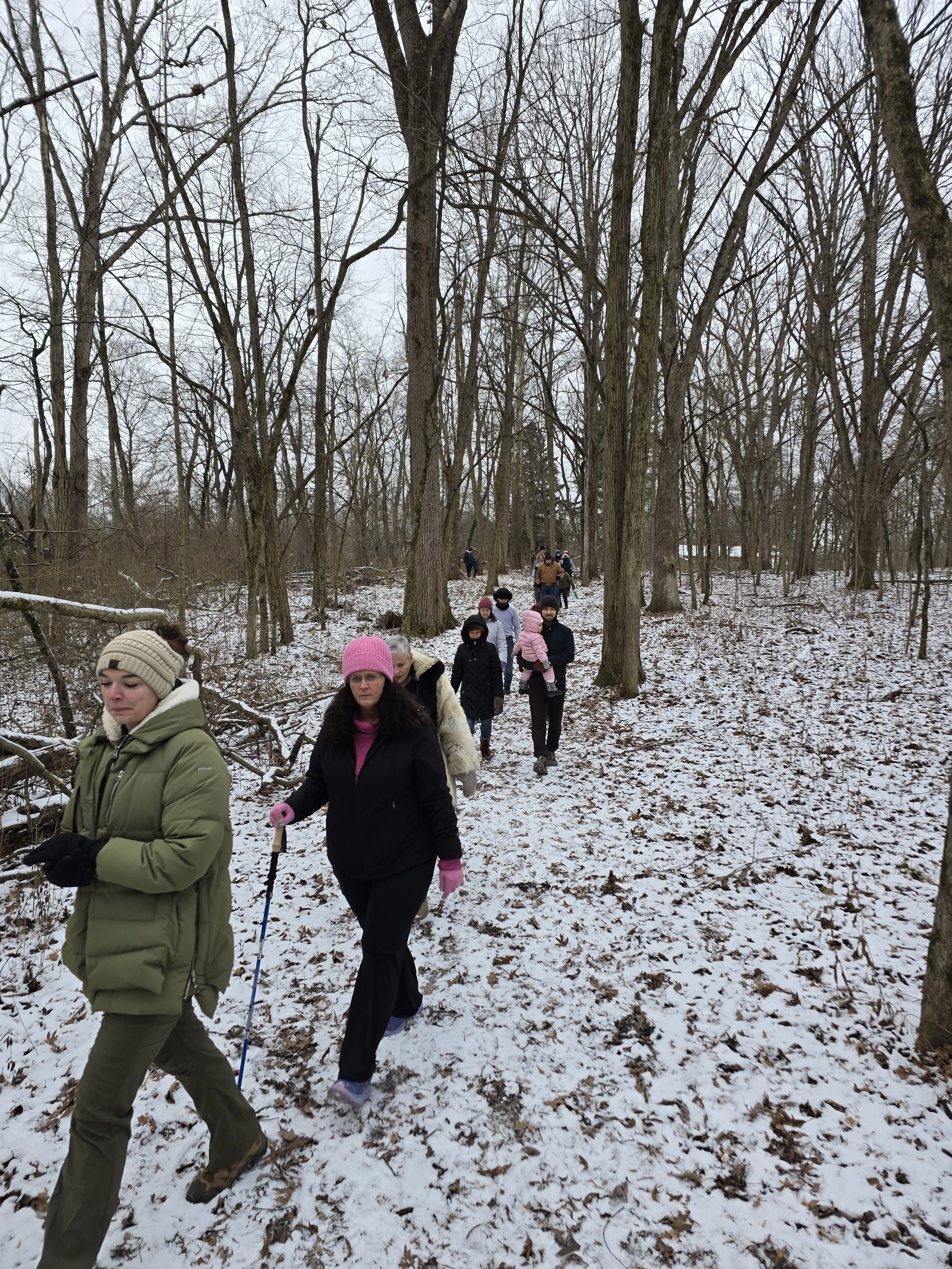 Group hiking on a dirt trail through a forest in winter