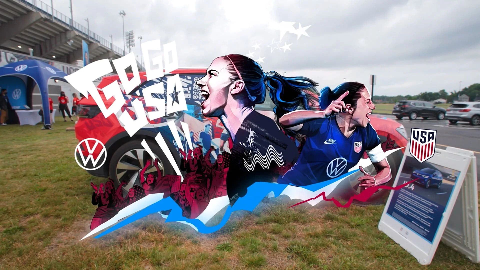 A large graphic banner at an outdoor sports event features female athletes wearing USA soccer jerseys with digital and illustrated artistic effects. Logos of Volkswagen and the USA Soccer team are visible. In the background, there are tents, a parking lot with cars, and a cloudy sky.