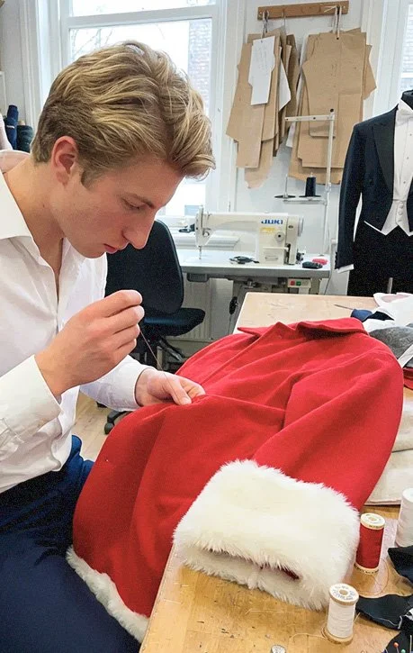 Person sewing a Santa Claus costume in a sewing workshop.