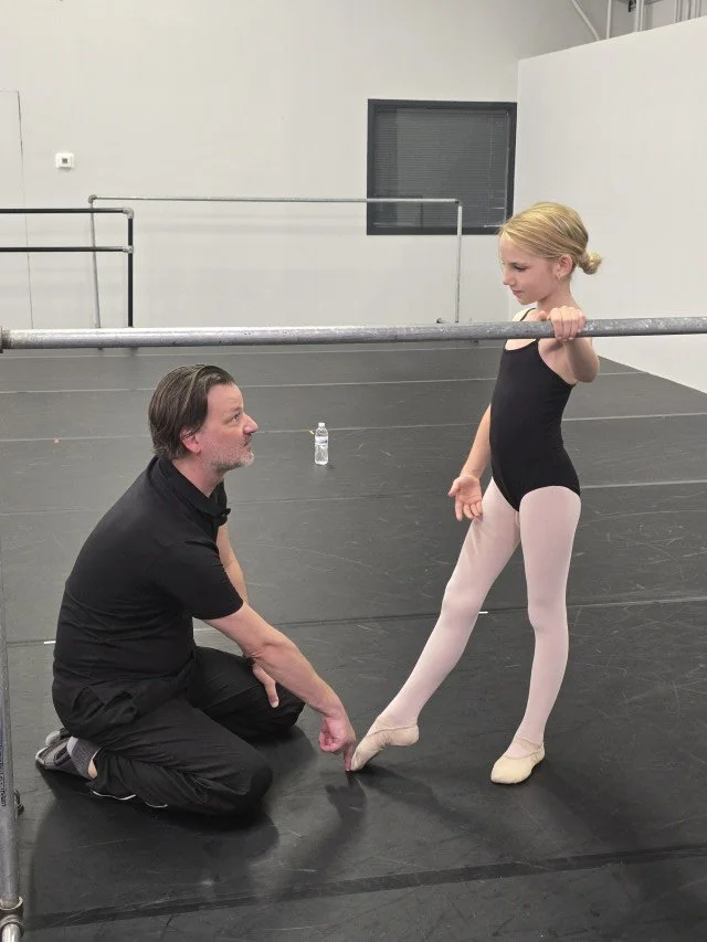 Logan Pachciarz giving focused technical coaching to a BalletCorps student