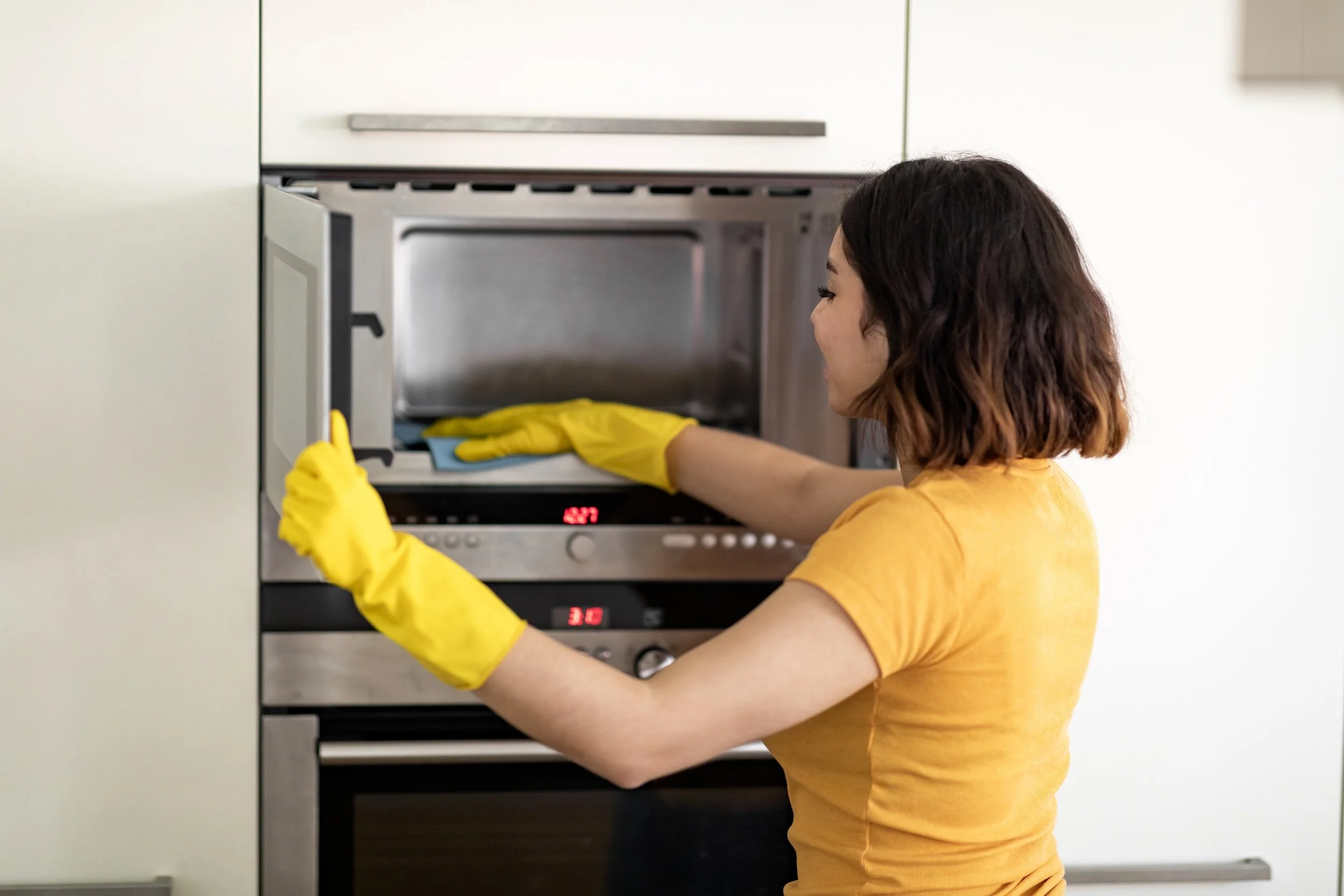 happy-young-arab-woman-wiping-microwave-with-rag-w-2023-11-27-05-01-38-utc.jpg