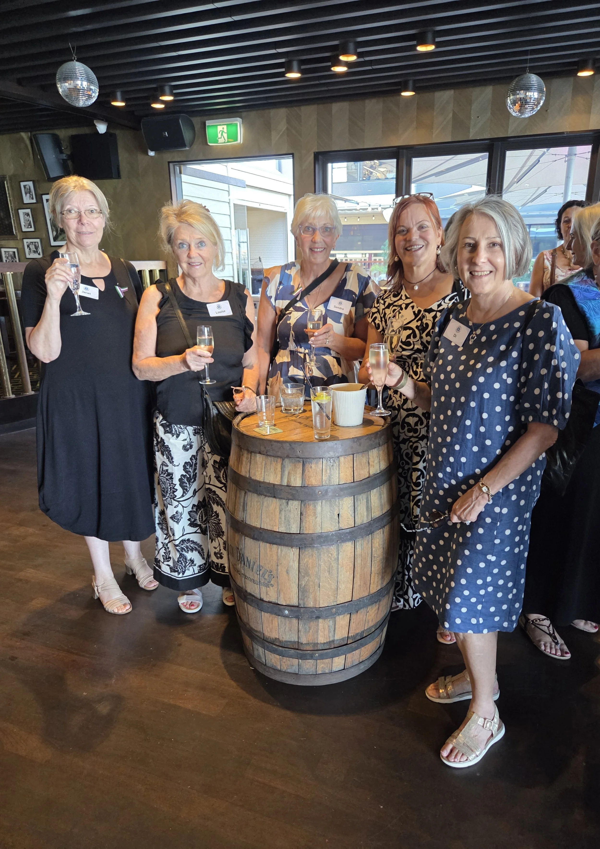 Group of women standing around a barrel enjoying drinks