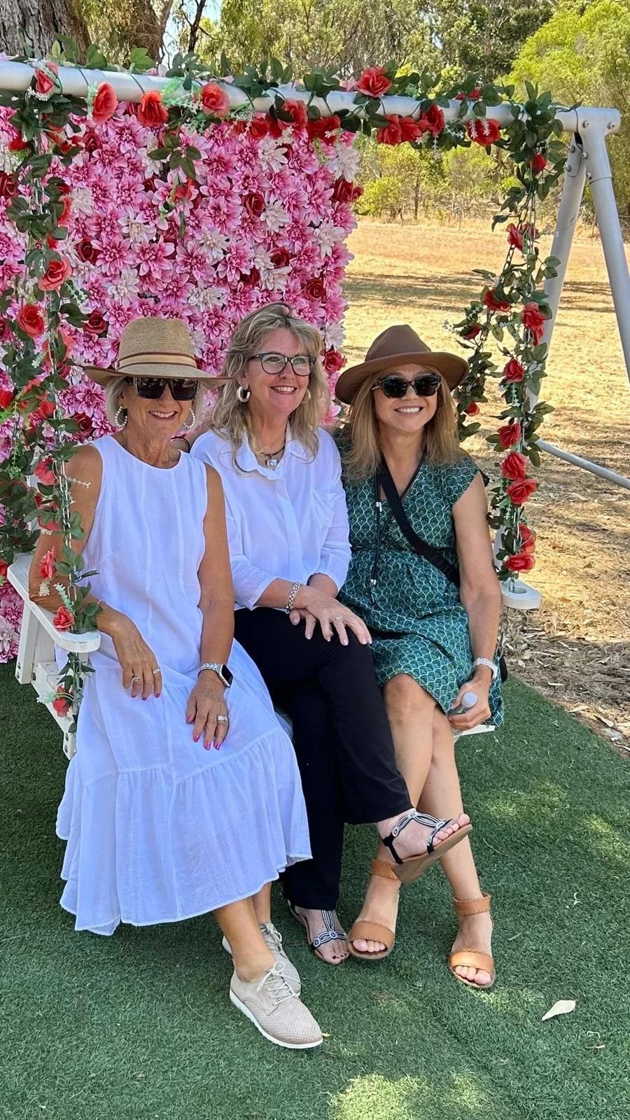 Three women sitting in front of flowers
