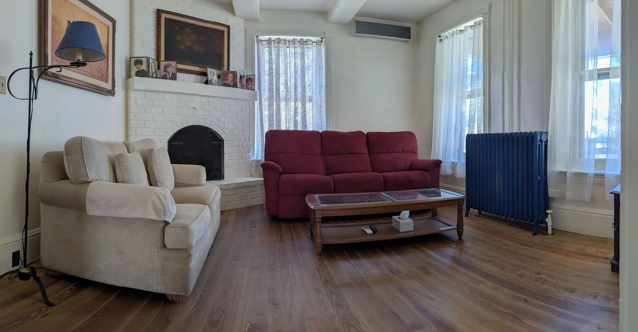Historic living room at Bella Vista Bed and Breakfast featuring original hardwood floors, comfortable seating, a fireplace, and abundant natural light in Akron, Pennsylvania.