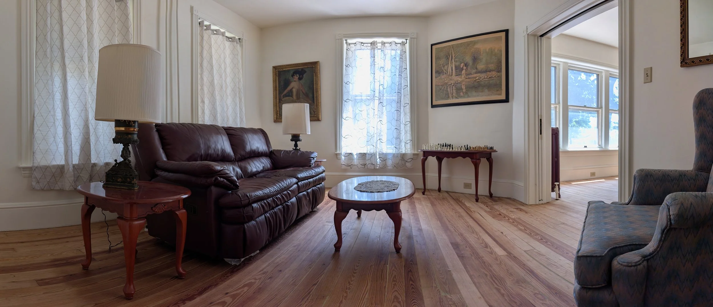Elegant historic parlor at Bella Vista Bed and Breakfast featuring original hardwood floors, antique furnishings, abundant natural light, and comfortable seating for guests in Akron, Pennsylvania.