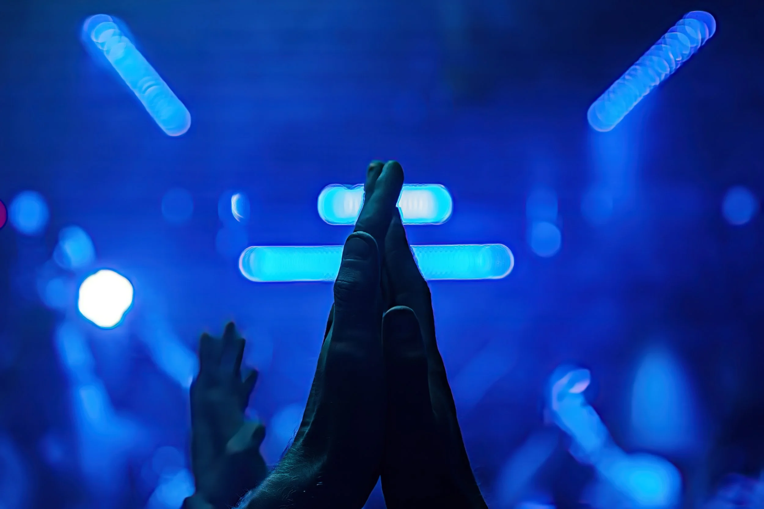 Jemand hebt die Hände in einem Dunkelraum mit blauer LED-Beleuchtung zusammen. 