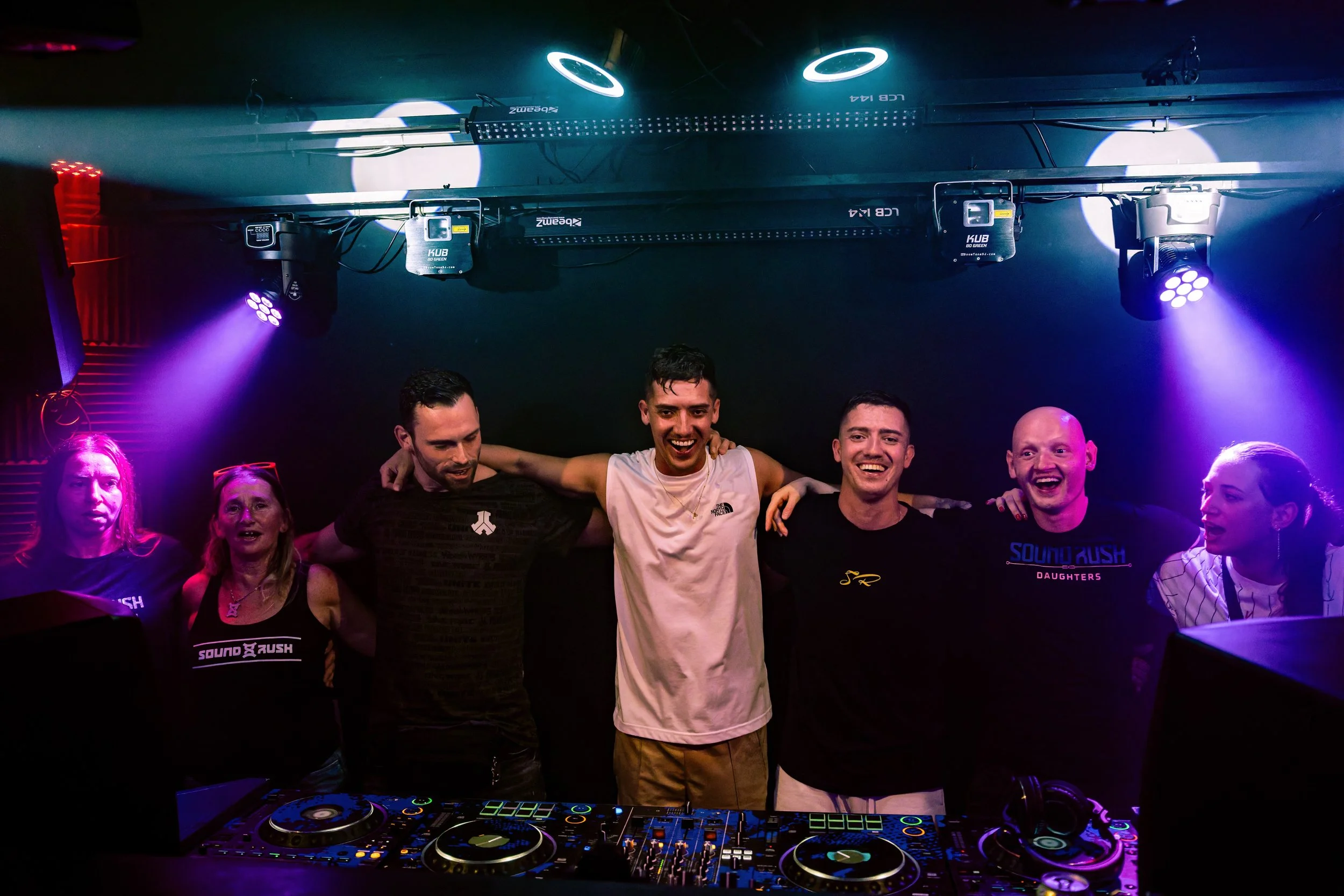 Junge Menschen feiern und tanzen in einem Club mit Diskokugel und Lichtshows.