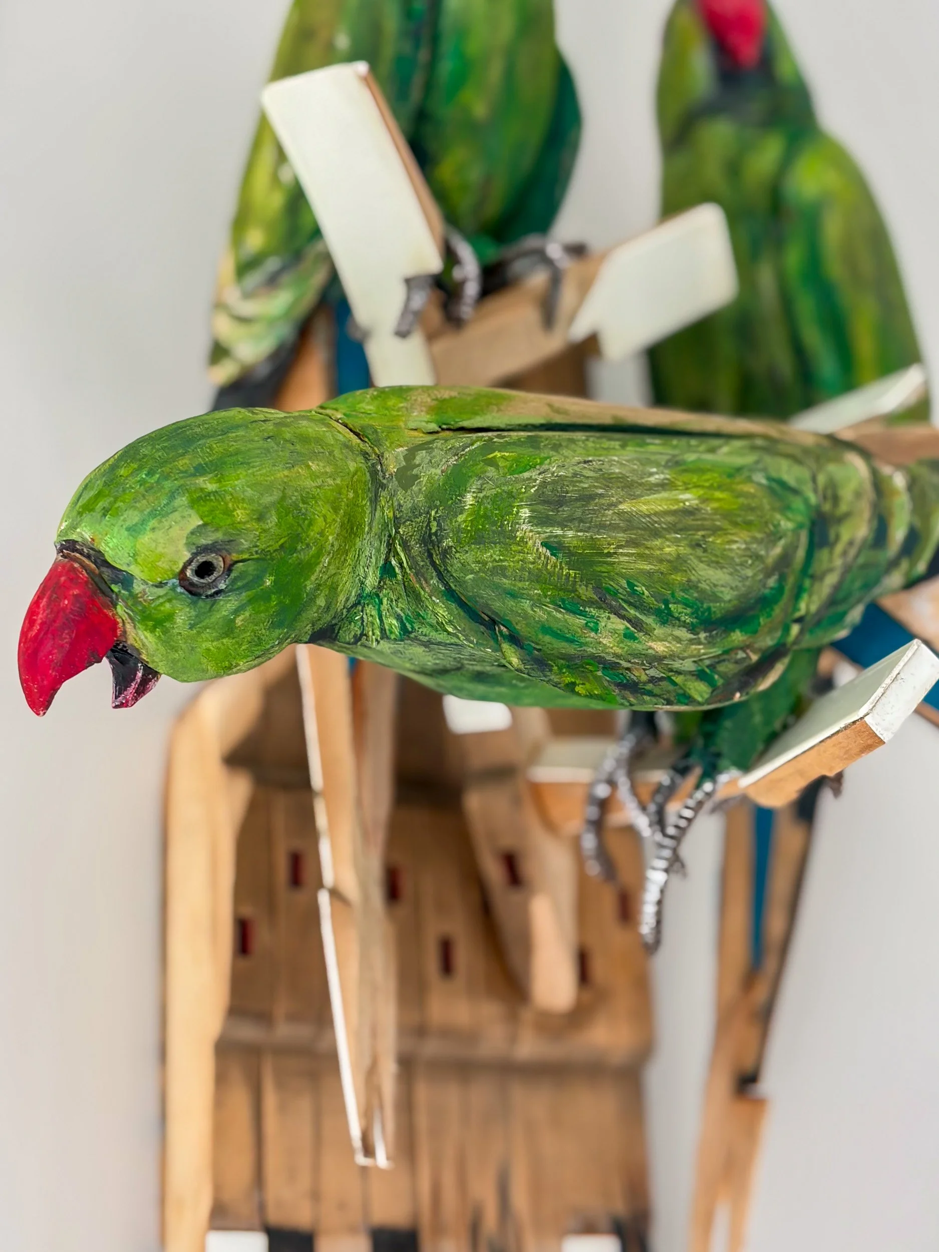Sculpture of Three Parakeets in F Minor made of piano parts with close up of bird detail.
