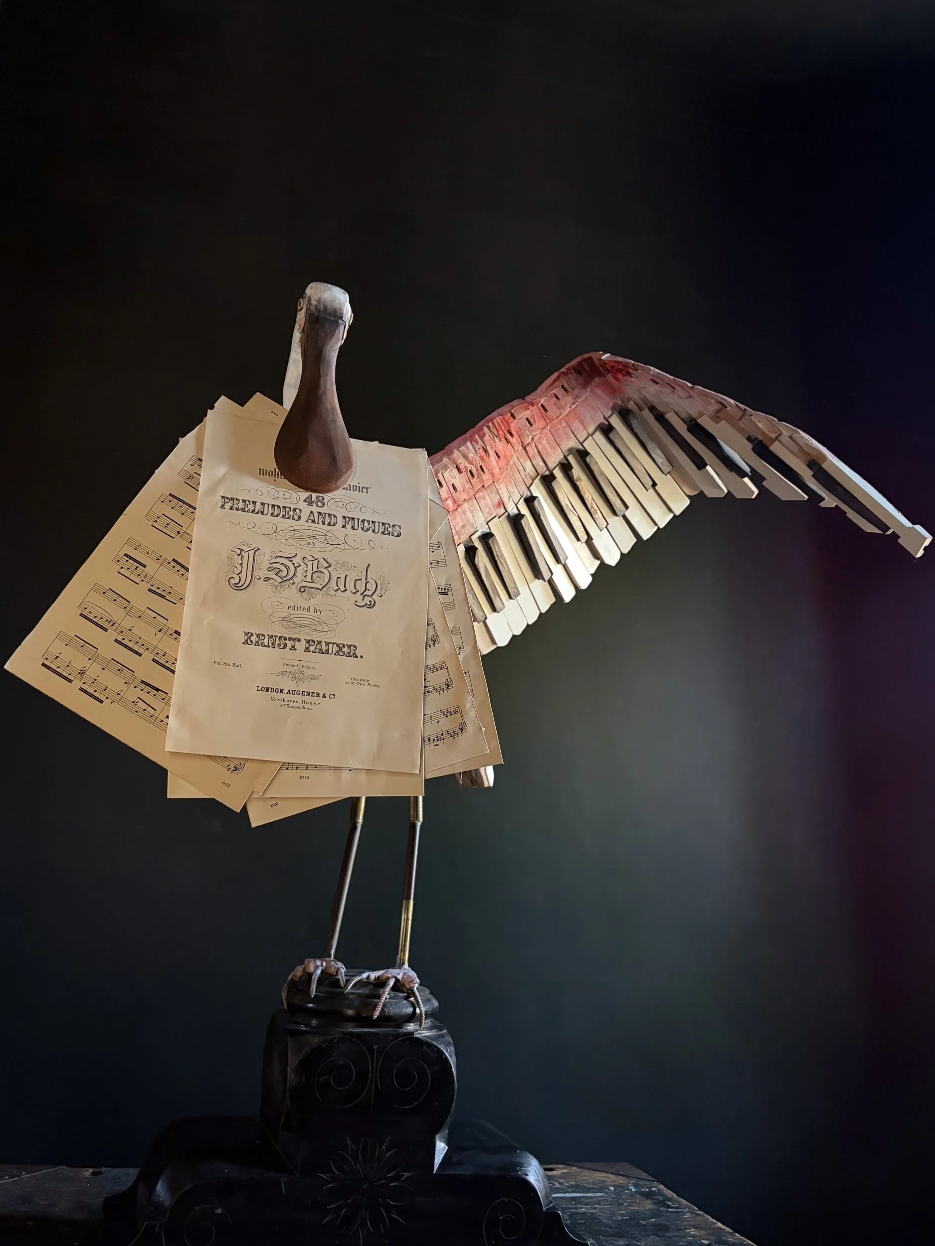 Roseate Spoonbill sculpture made from piano parts shown with piano sheet music in bill.