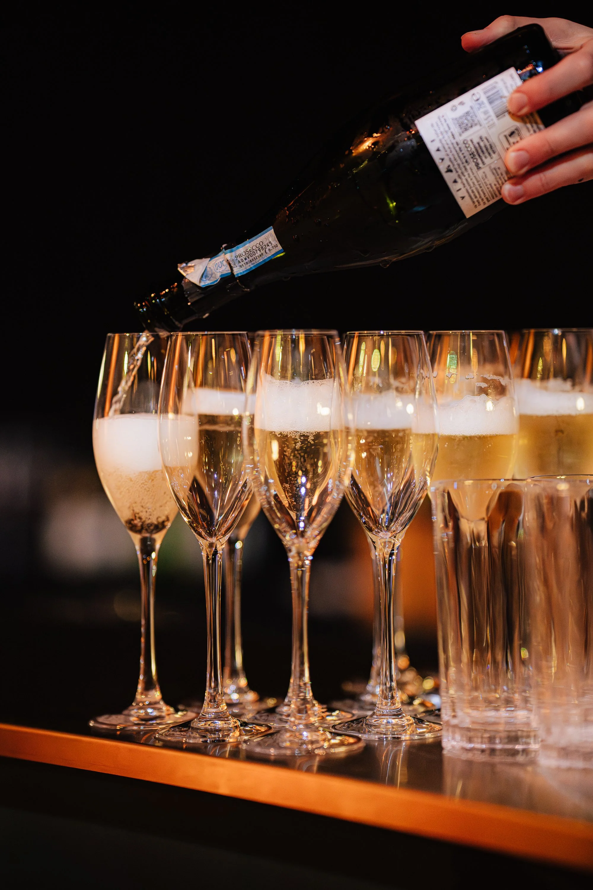 Person pouring champagne into flutes at a celebration.