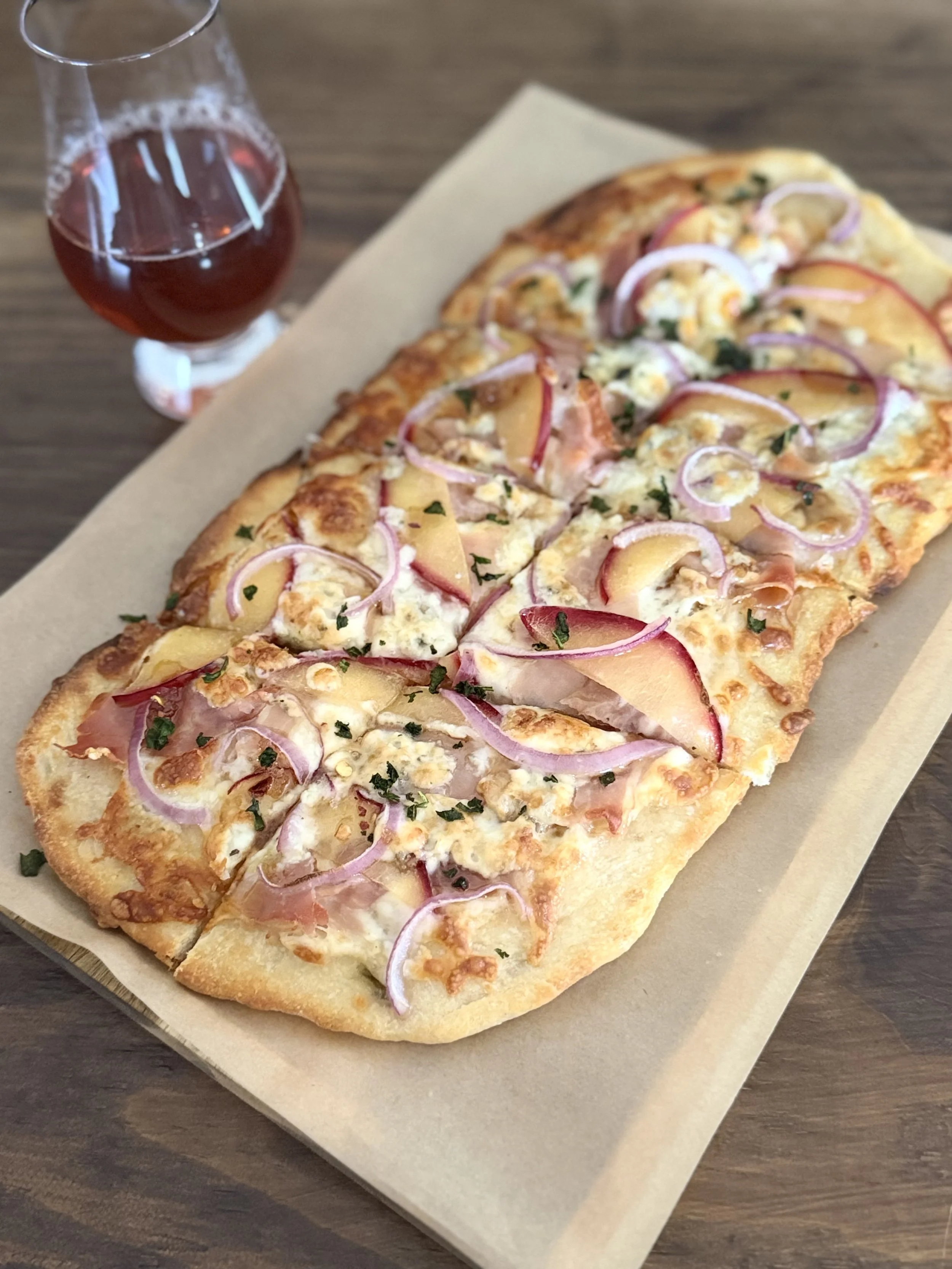 Vinland The Plumage flatbread with plum slices, cheese and red onion