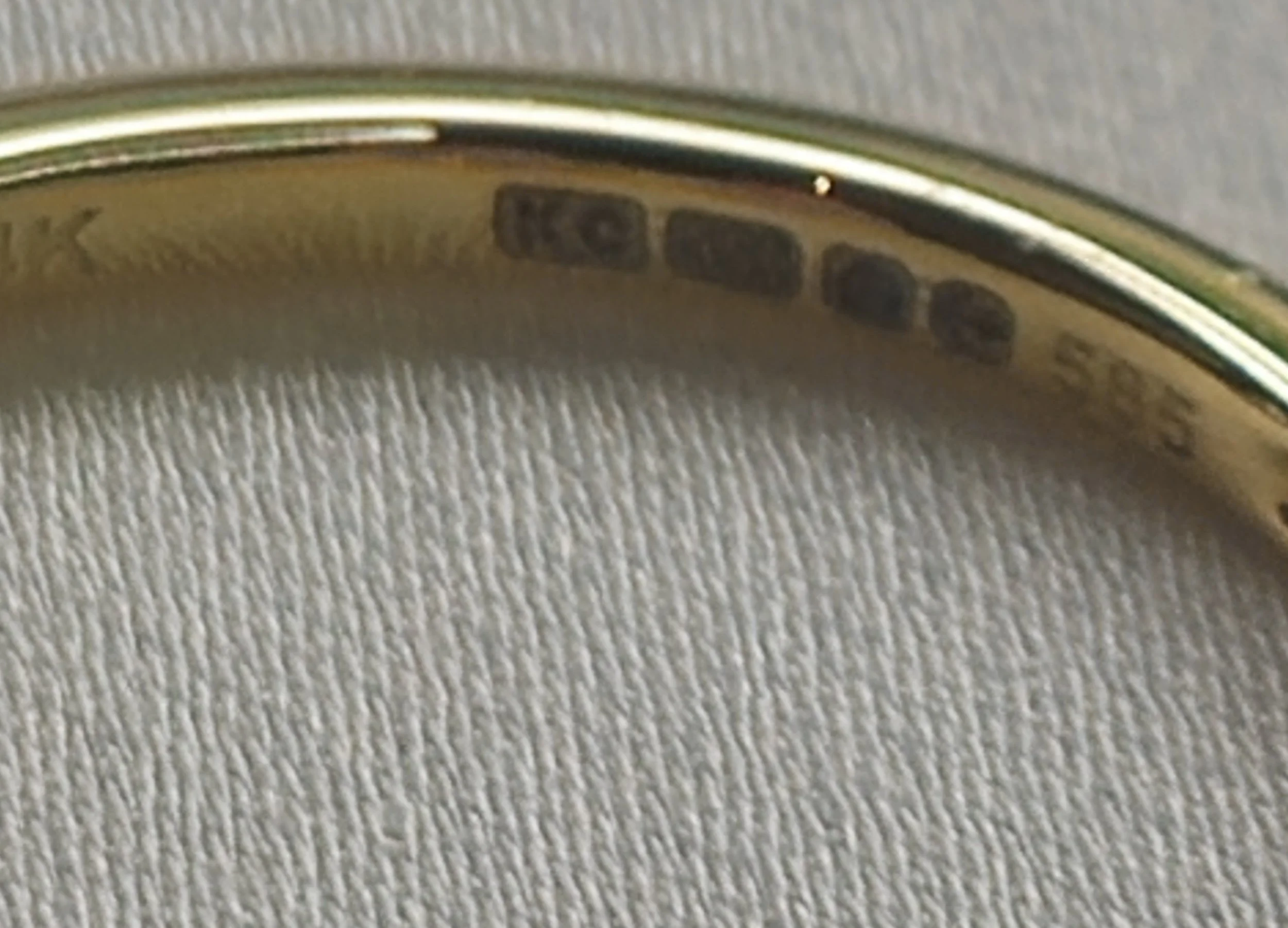 Close-up of a stainless steel watch case with hallmarks and serial numbers engraved on the inner surface.