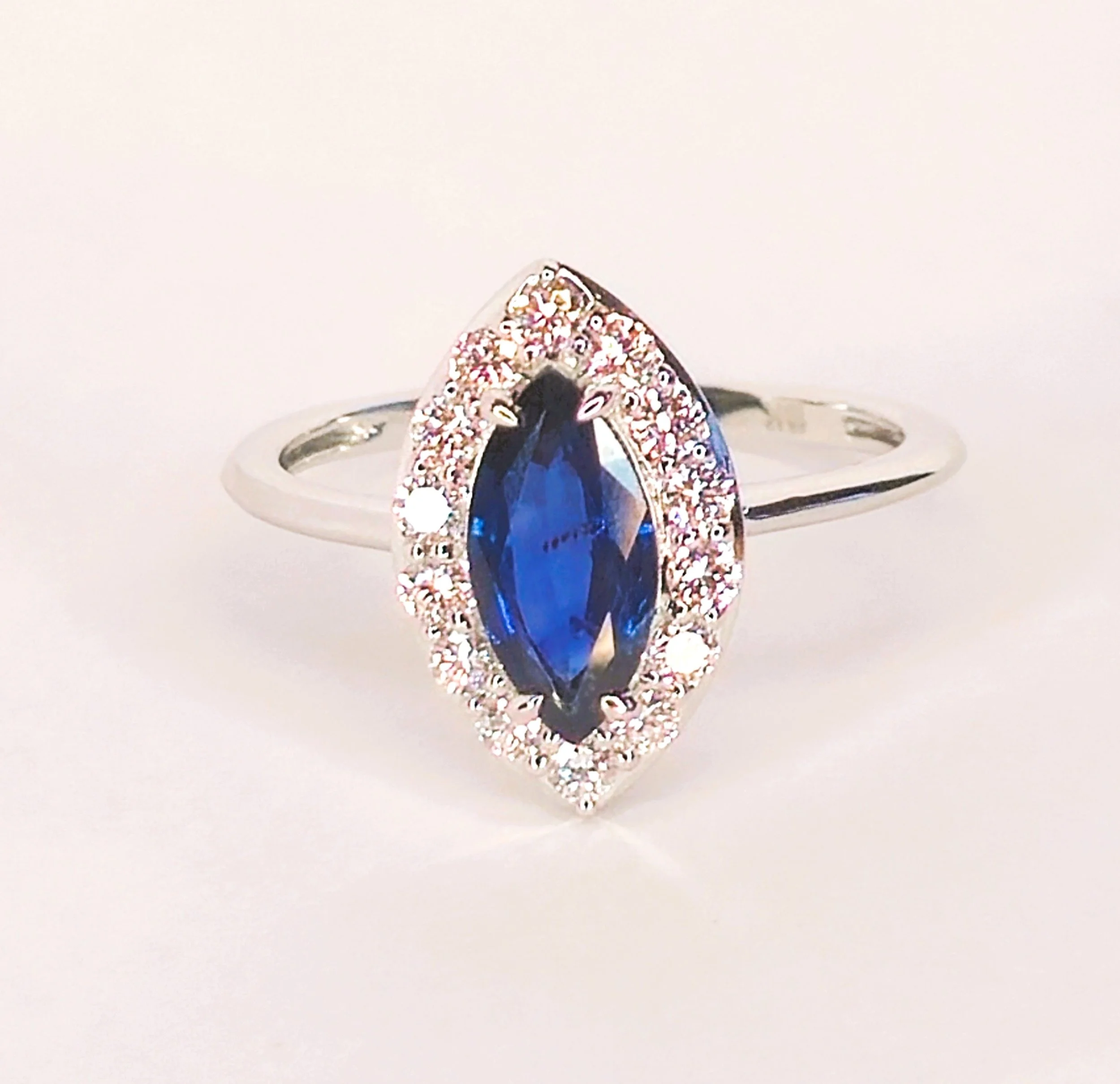 A refined alternative engagement ring showcasing an unheated marquise-cut Kanchanaburi blue sapphire, surrounded by sparkling diamonds. Handcrafted with a timeless silhouette inspired by royal jewellery, celebrating natural beauty.