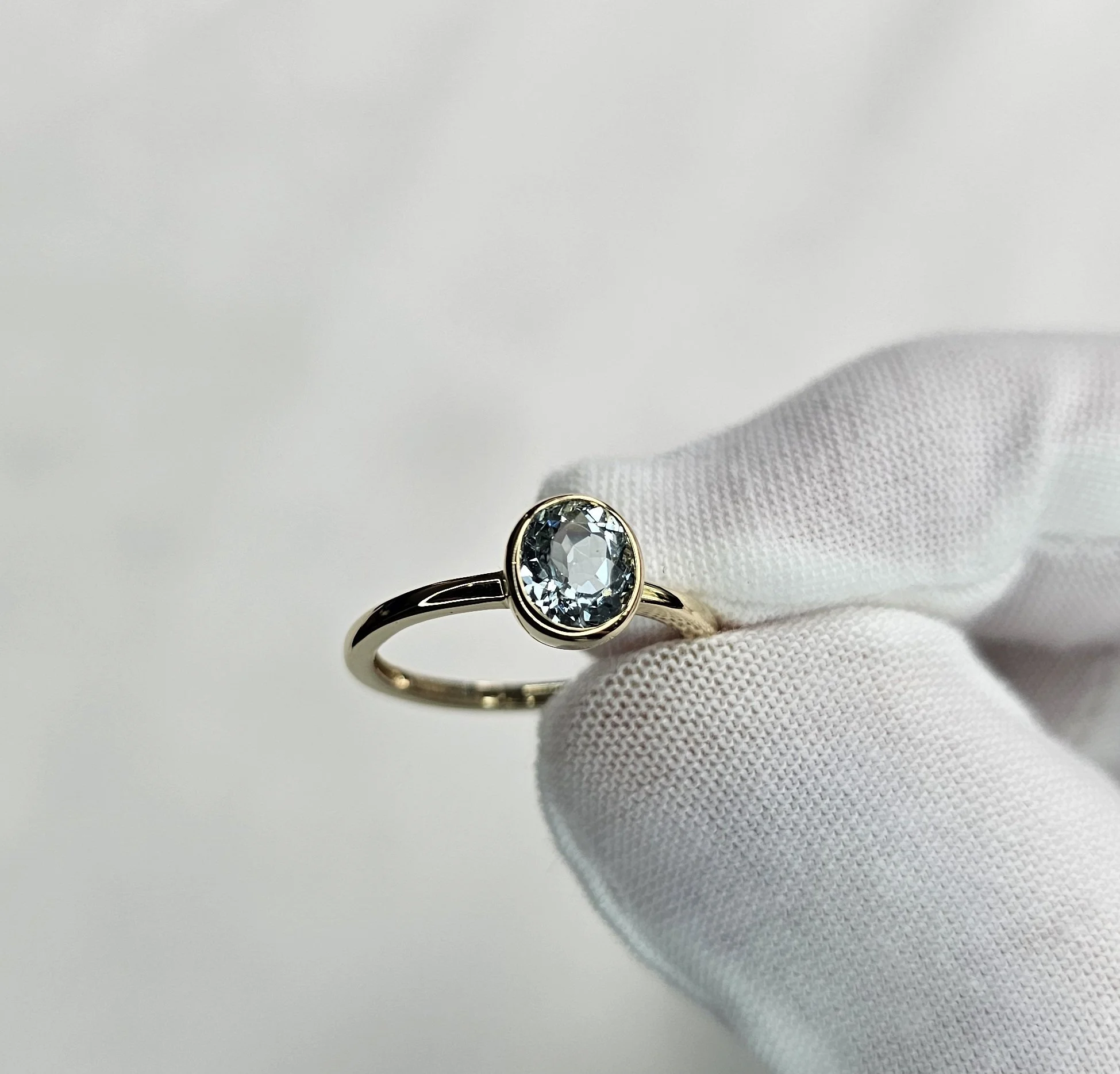 A refined 14k yellow gold ring featuring a natural aquamarine in a sleek bezel setting, designed for everyday elegance and longevity. The ring is undergoing our inspection prior to shipment.