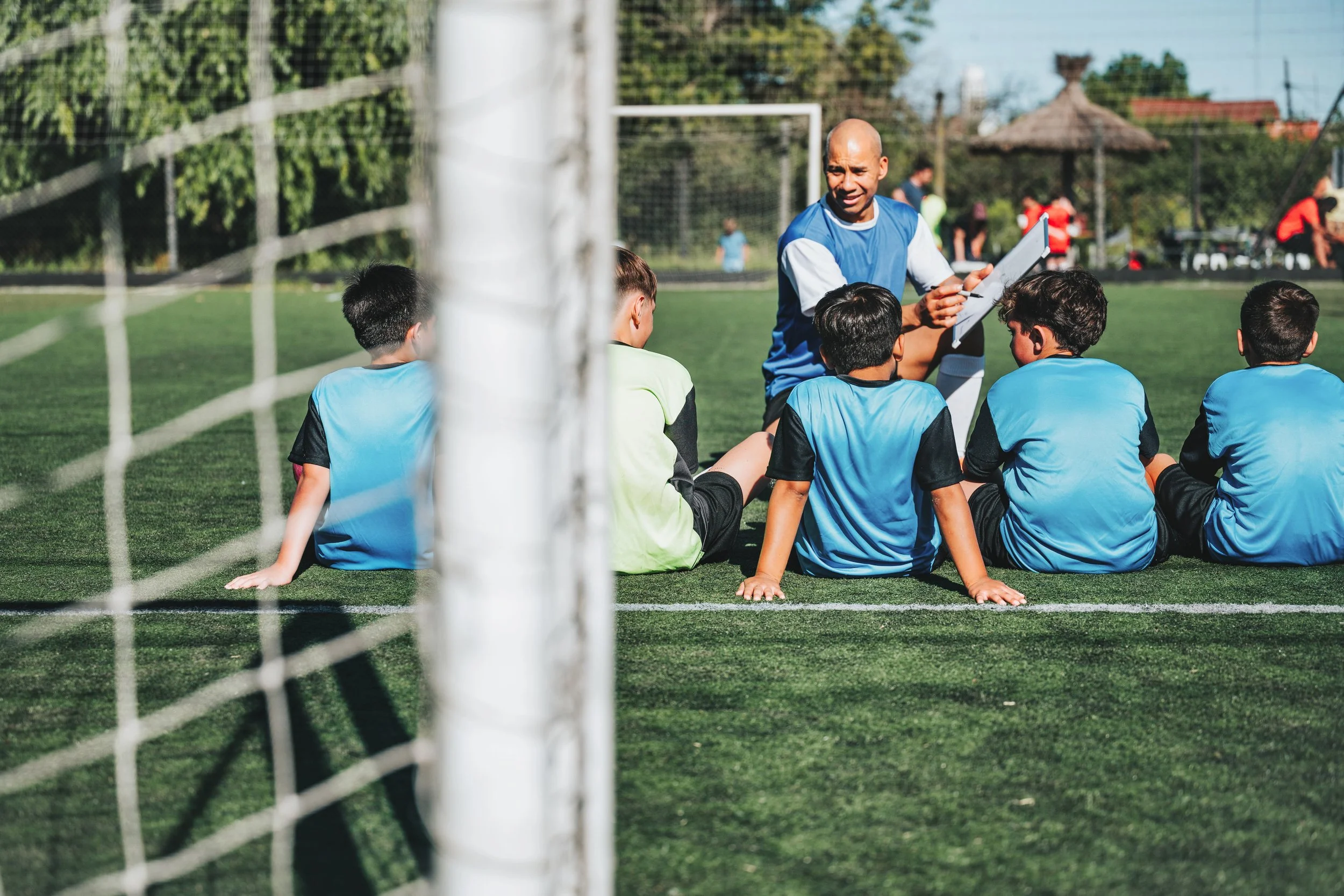 Youth soccer coach showing a small group of boys the plays for their next game.