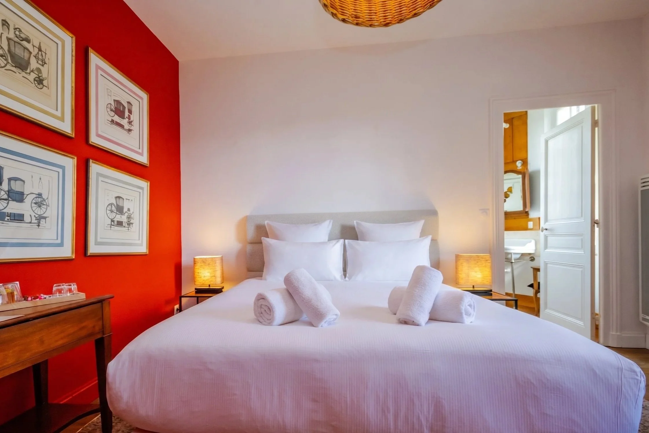 Chambre avec lit double, tête de lit en bois, éclairage intégré, porte ouverte vers une salle de bain avec vasque en bois.