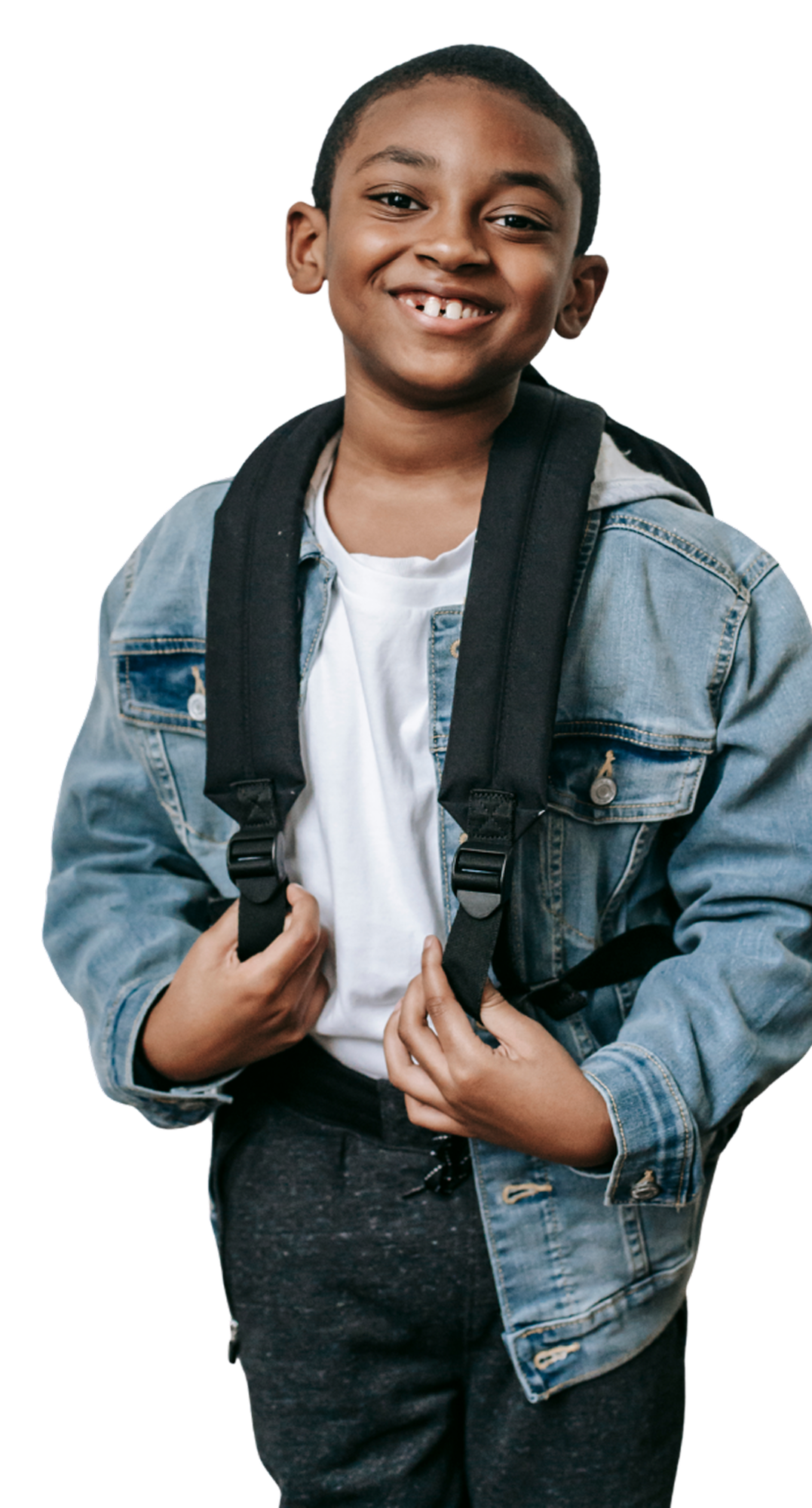 Smiling young boy with short hair wearing a denim jacket, white T-shirt, and backpack, standing confidently.