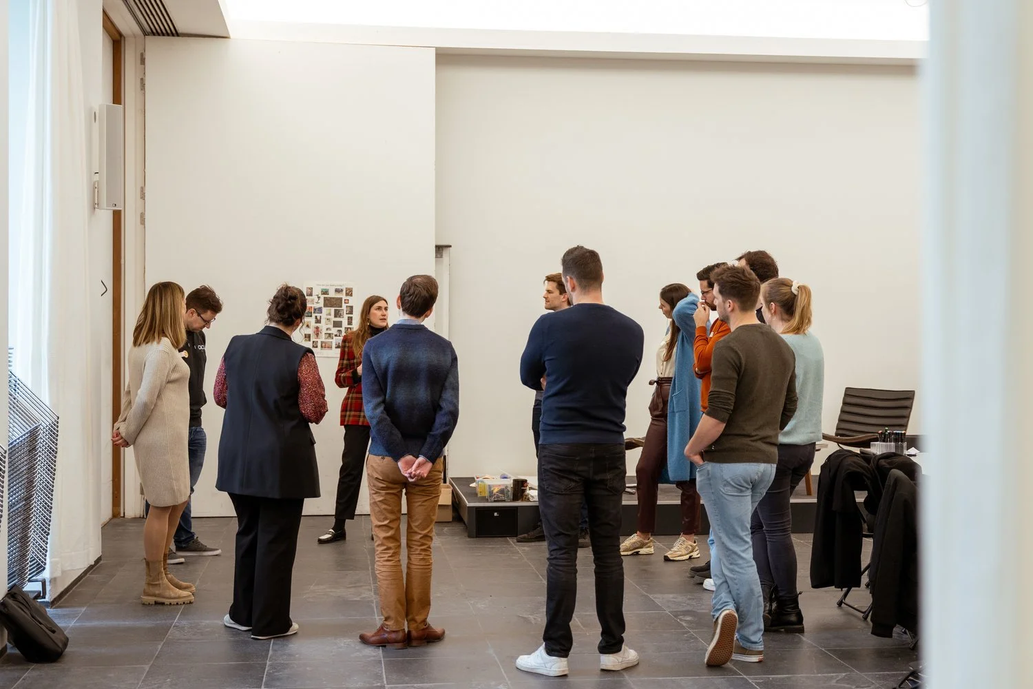 Group of people standing in circle in a conference or workshop room.