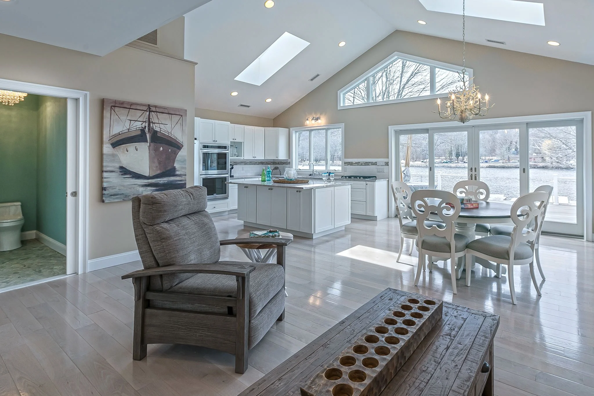The living room opens like a breath — pale textures, quiet lines, and views that never forget the river beyond. Here, comfort meets clarity. The design softens edges, layers light, and invites the landscape to take the lead.