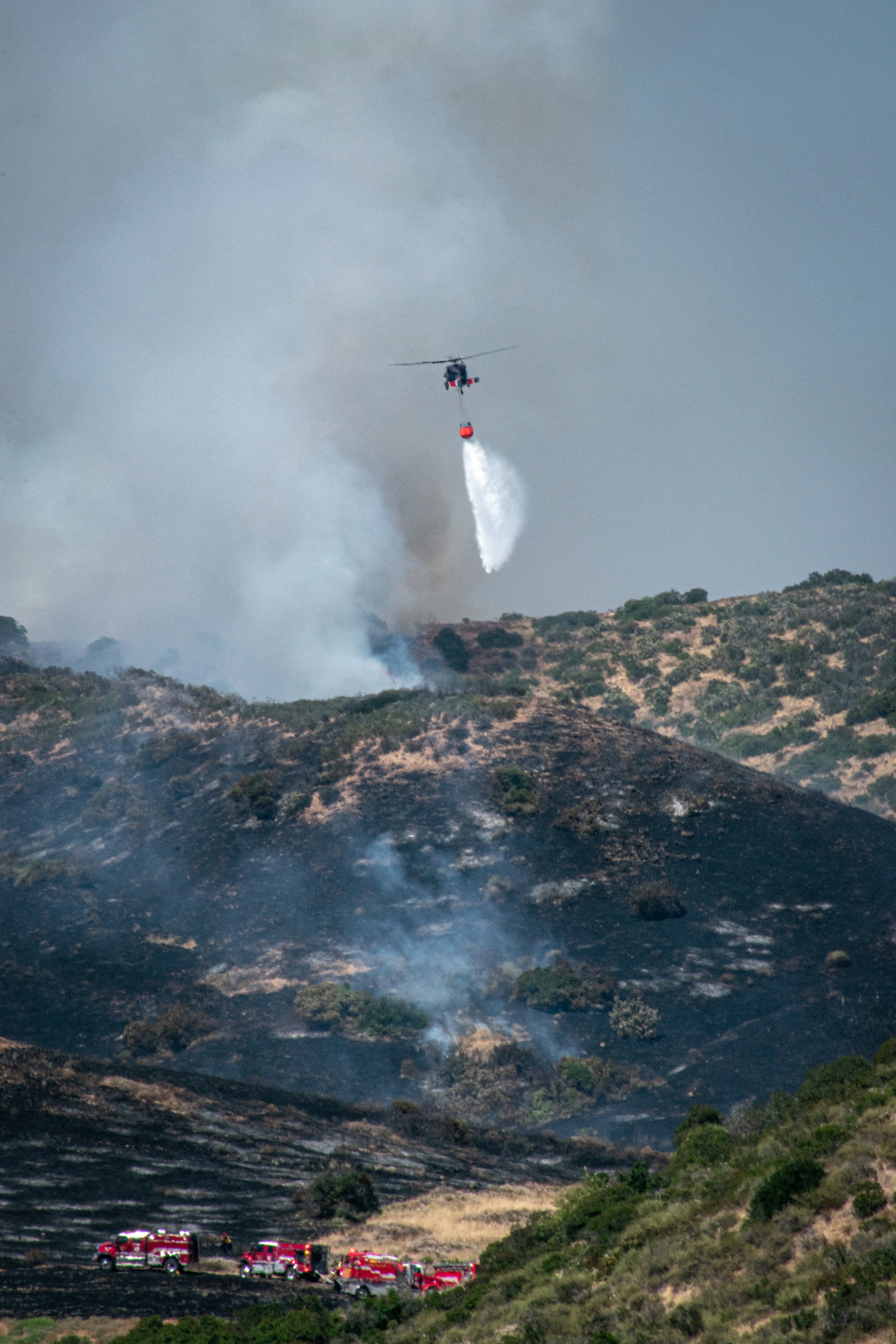 Helicopter over mountains putting out a fire
