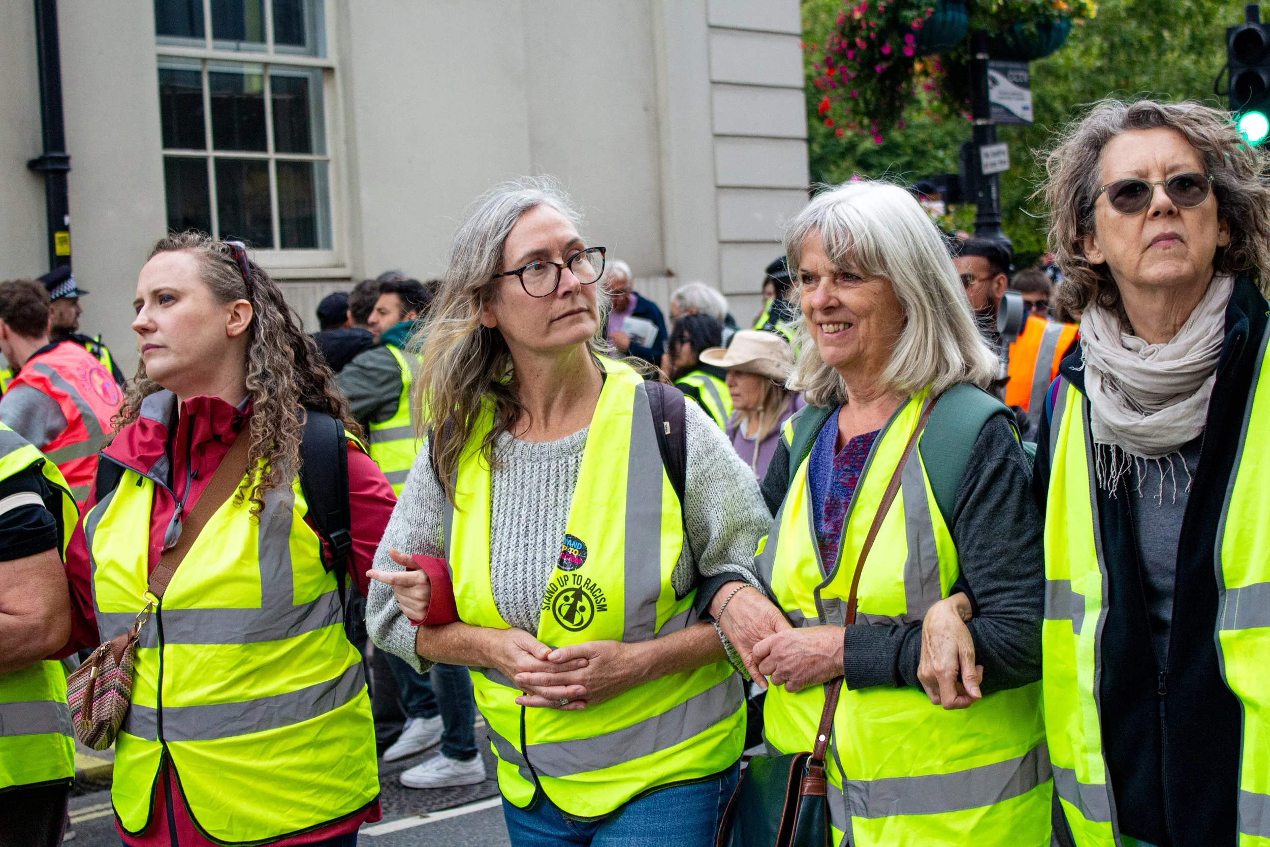 A line of female stewards for the counter protest link arms as the march continues down into the centre.