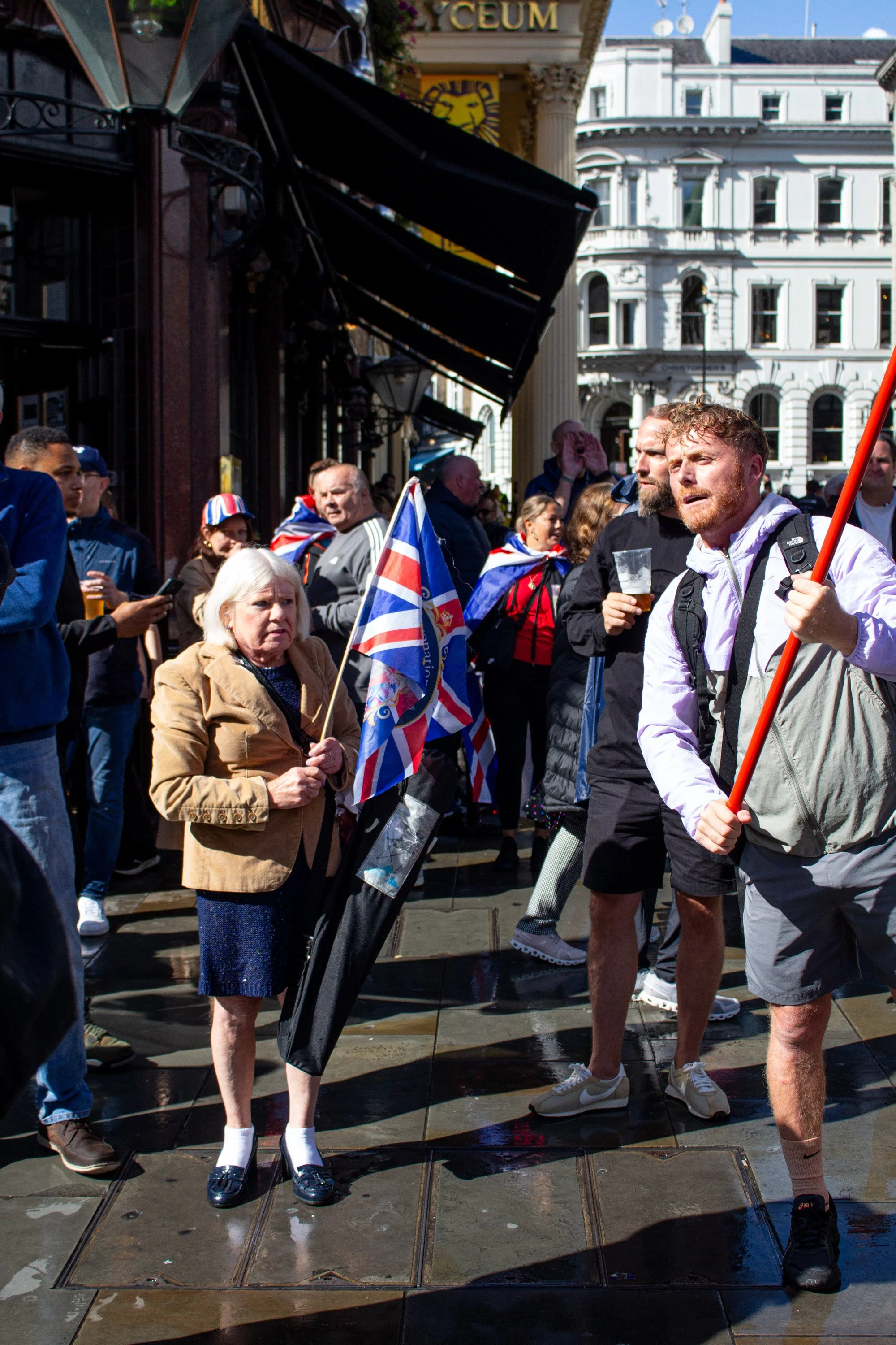 An elderly lady holds the British flag embossed with a portrait of the British royal family.
