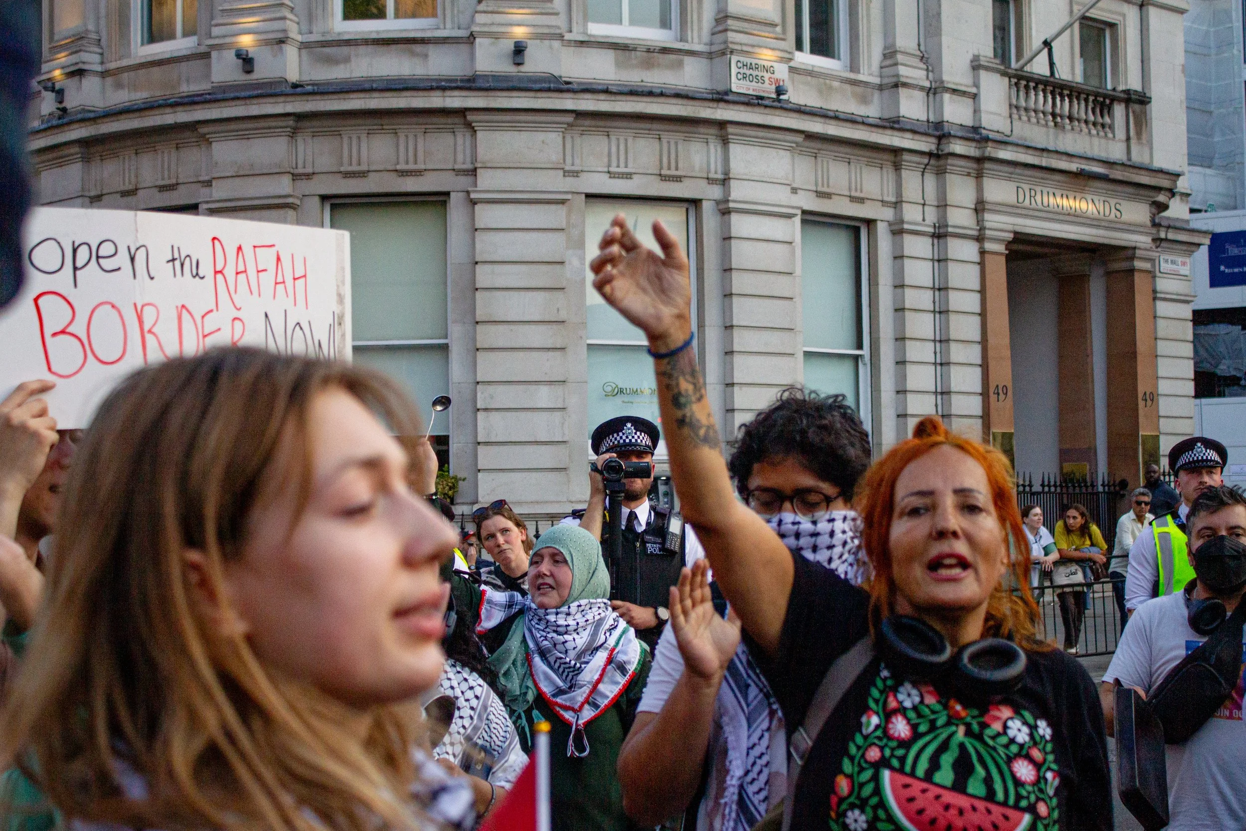 A policeman films protestors as they block the Trafalgar Square roundabout in protest of the ongoing genocide and famine in Gaza, 2025.