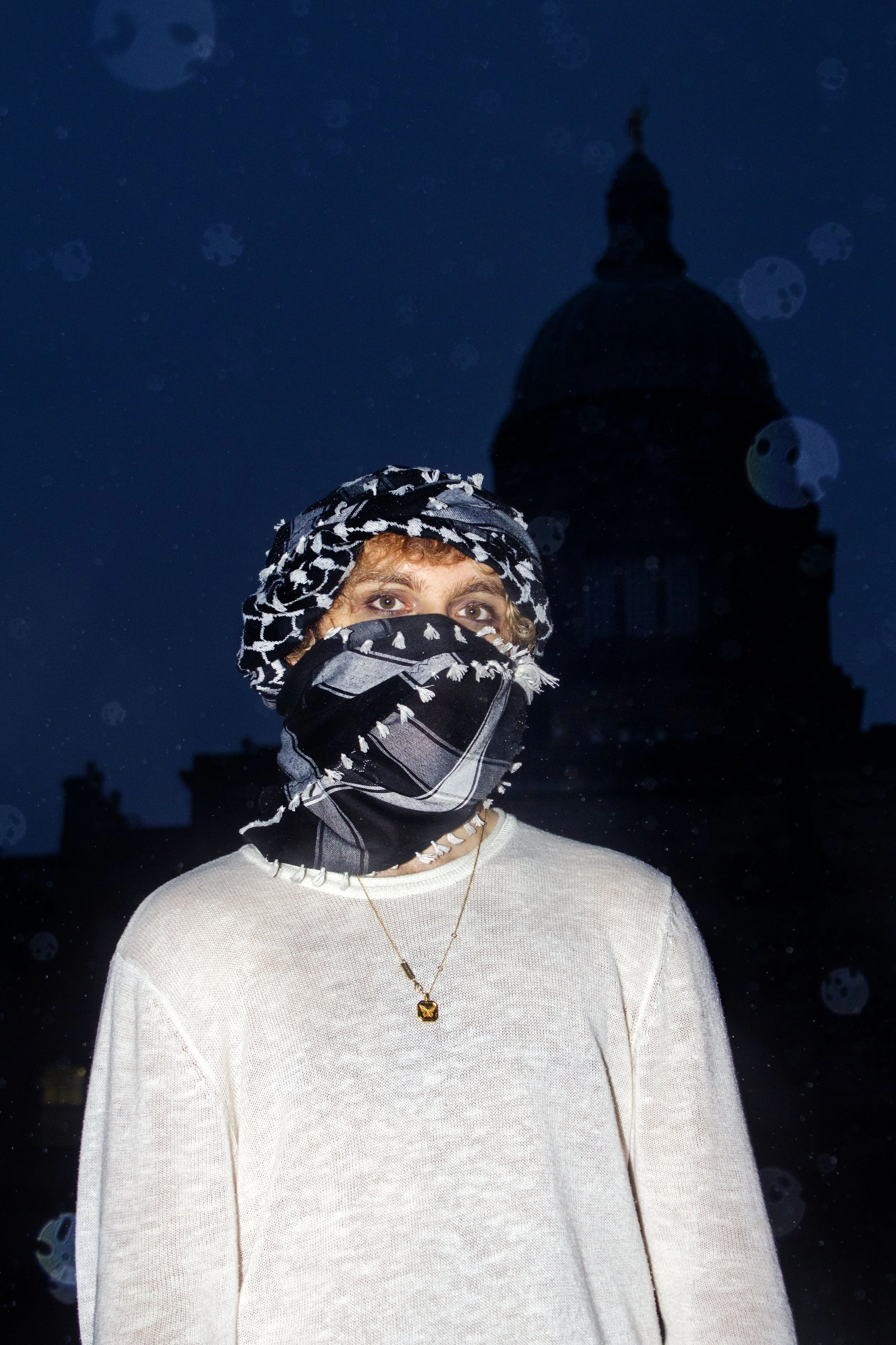A student on hunger strike stands in front of the dome of Old College, where the executive offices look over the student encampment, 2024.