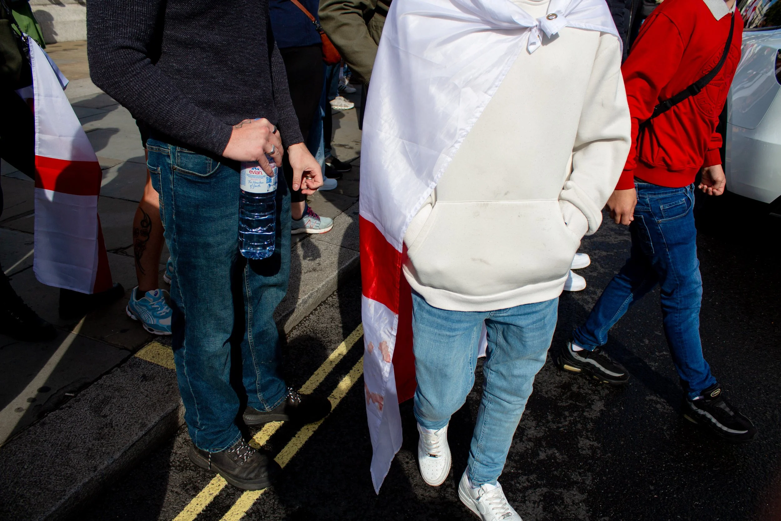 A man wearing the English flag walks towards the photographer.