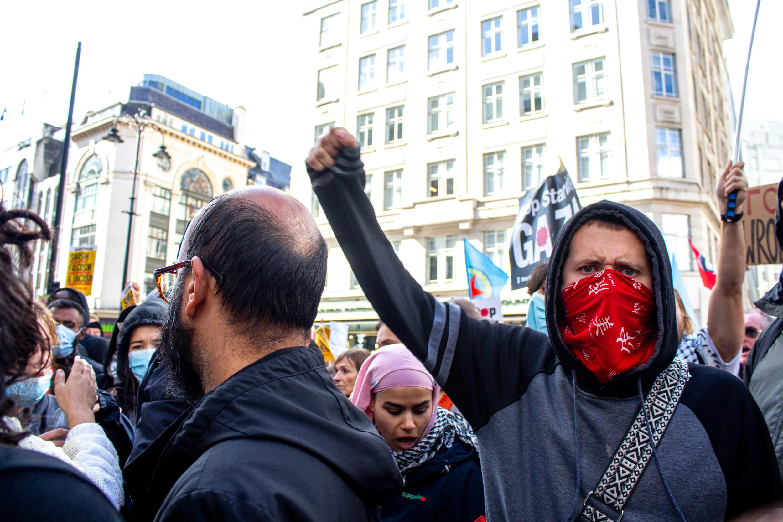 A member of the counter protests raises his fist while another masked member is being arrested.