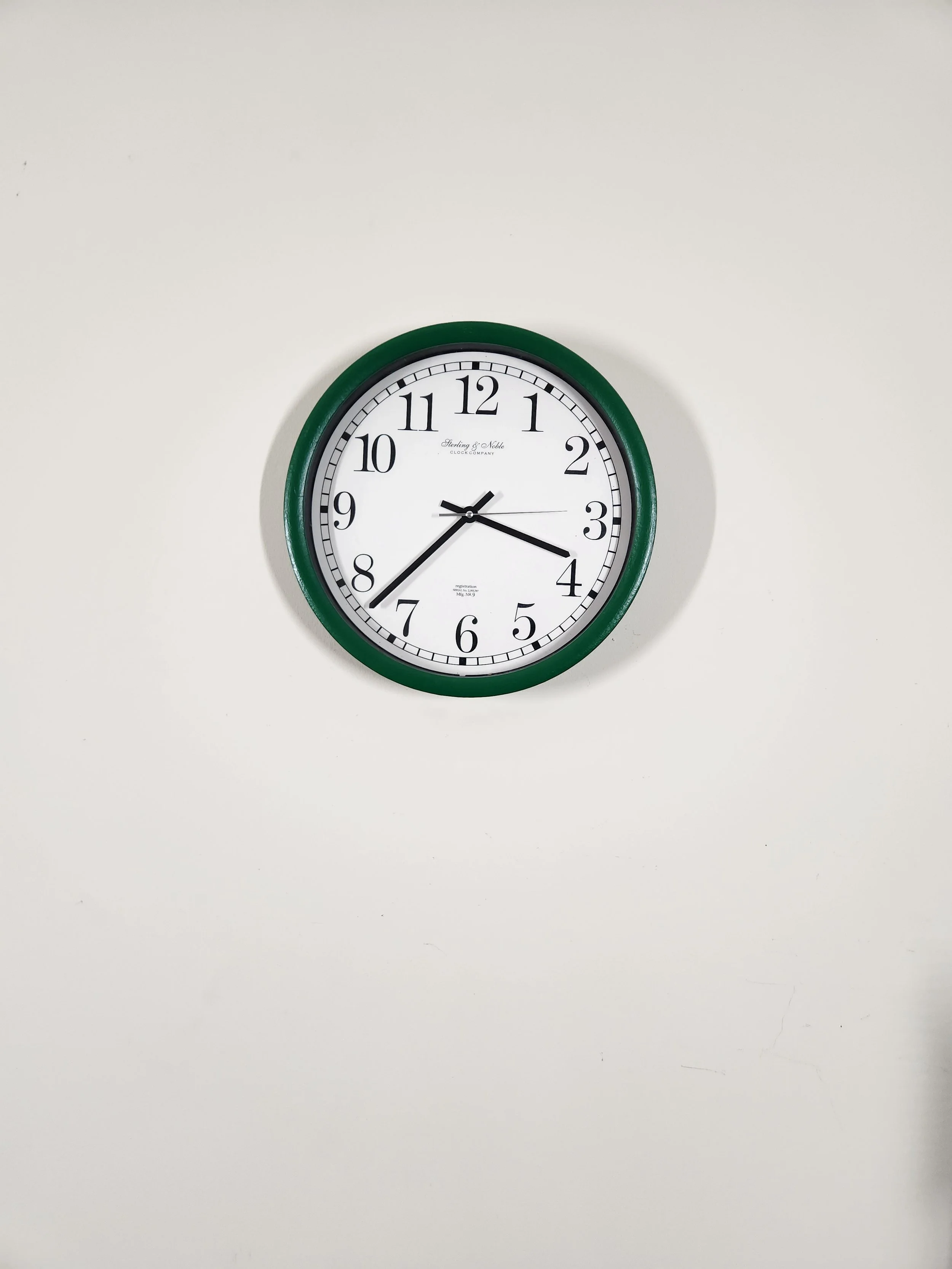 A round wall clock with a green frame showing the time as 1:39.