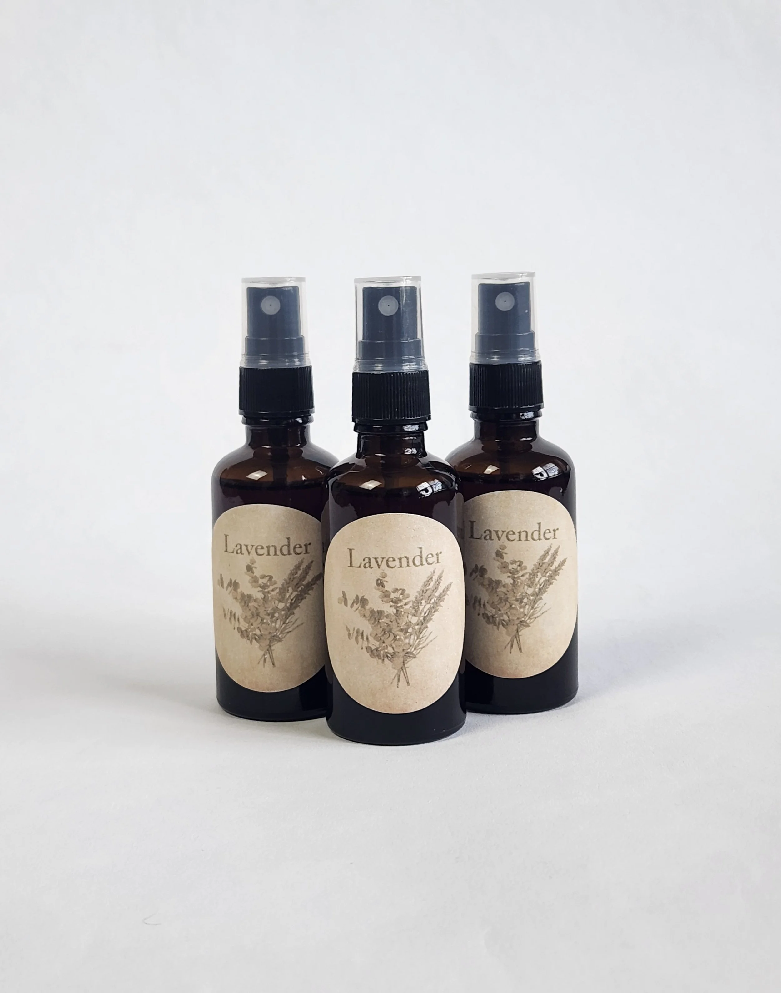 Three brown spray bottles labeled "Lavender" with beige labels featuring illustrations of lavender flowers, set against a plain white background.