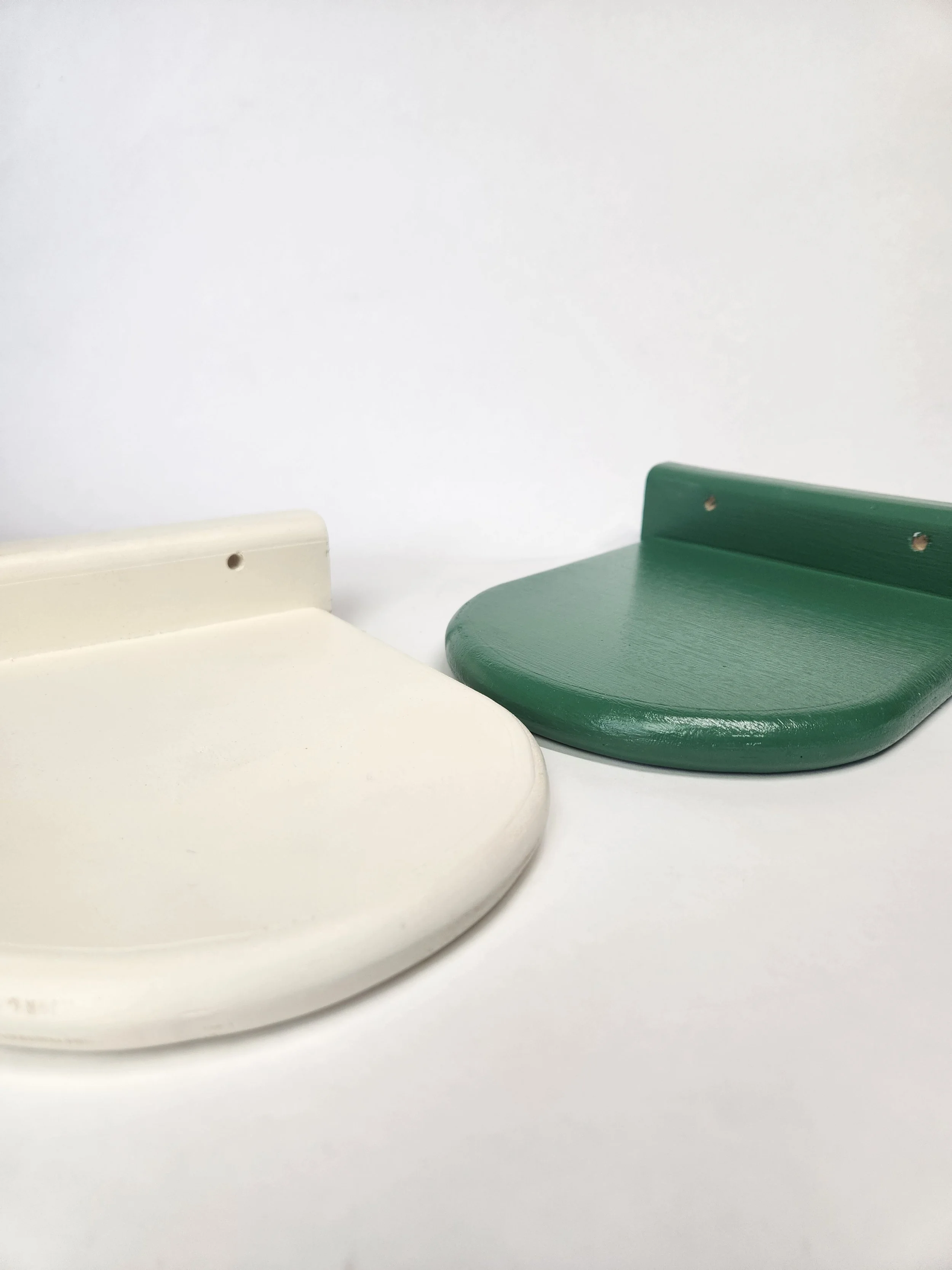 Close-up of two floating shelves, one white and one green, against a plain white background.