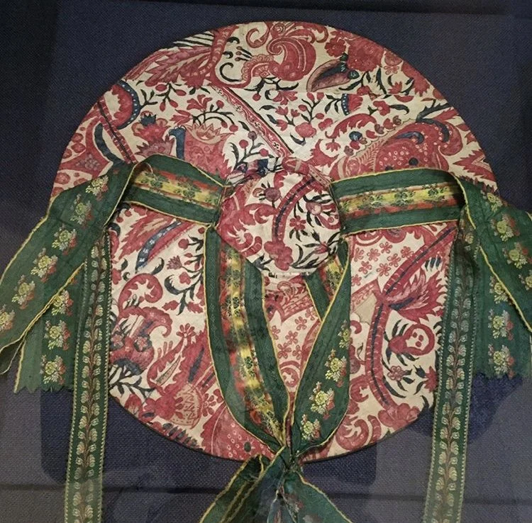 Decorative fabric with floral and animal patterns, tied with a green ribbon, on a circular surface.