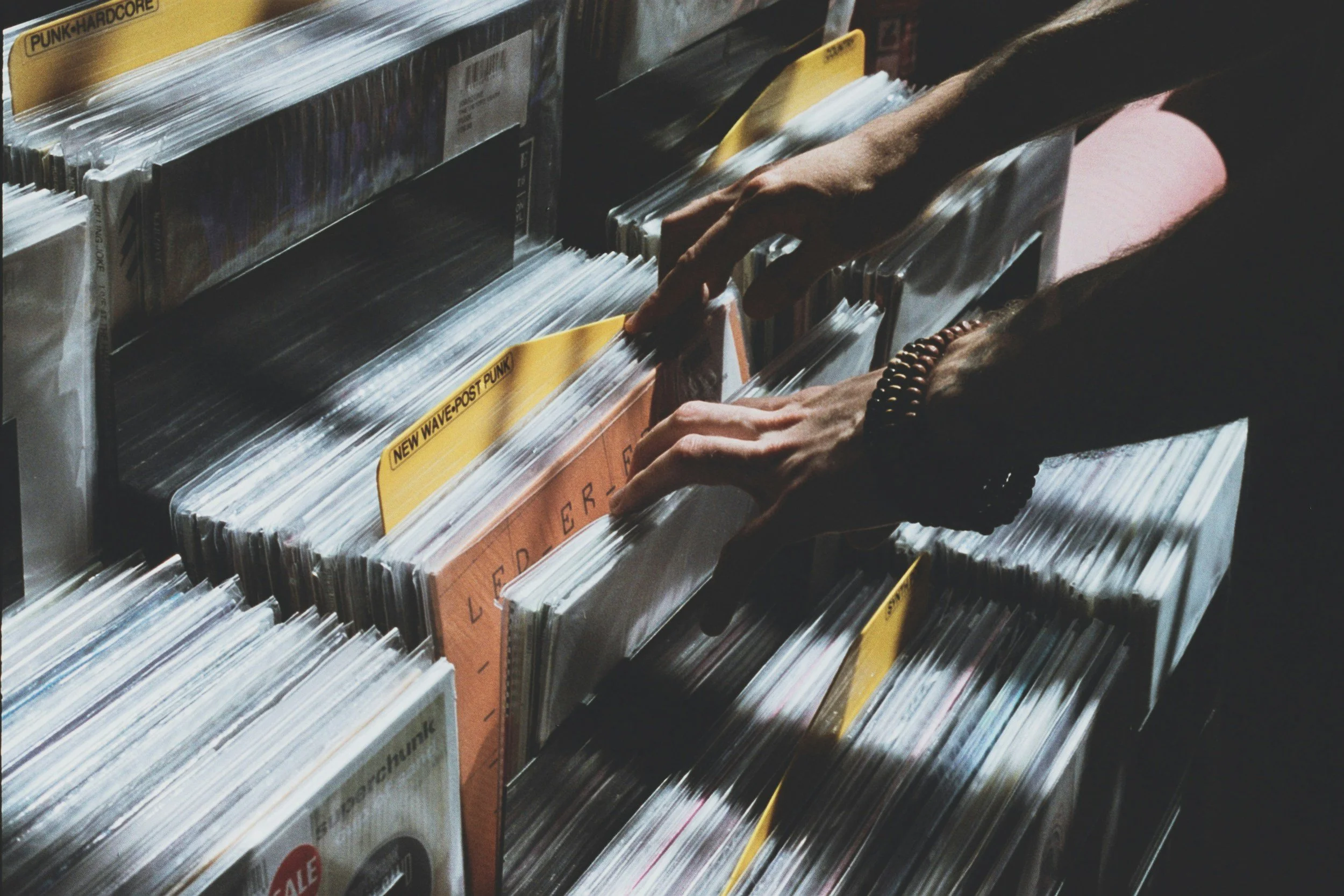 An image of someones hands in a Vinyl store searching through the stock