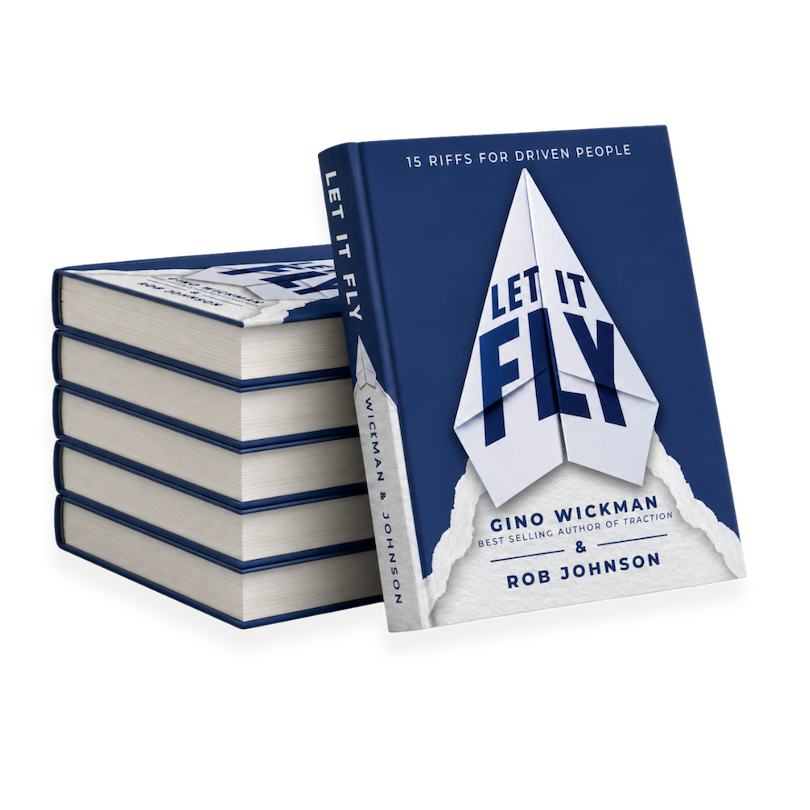 A stack of seven copies of the book "Let It Fly" by Gino Wickman and Rob Johnson, with one copy slightly tilted, displaying the cover featuring a paper airplane and the title.