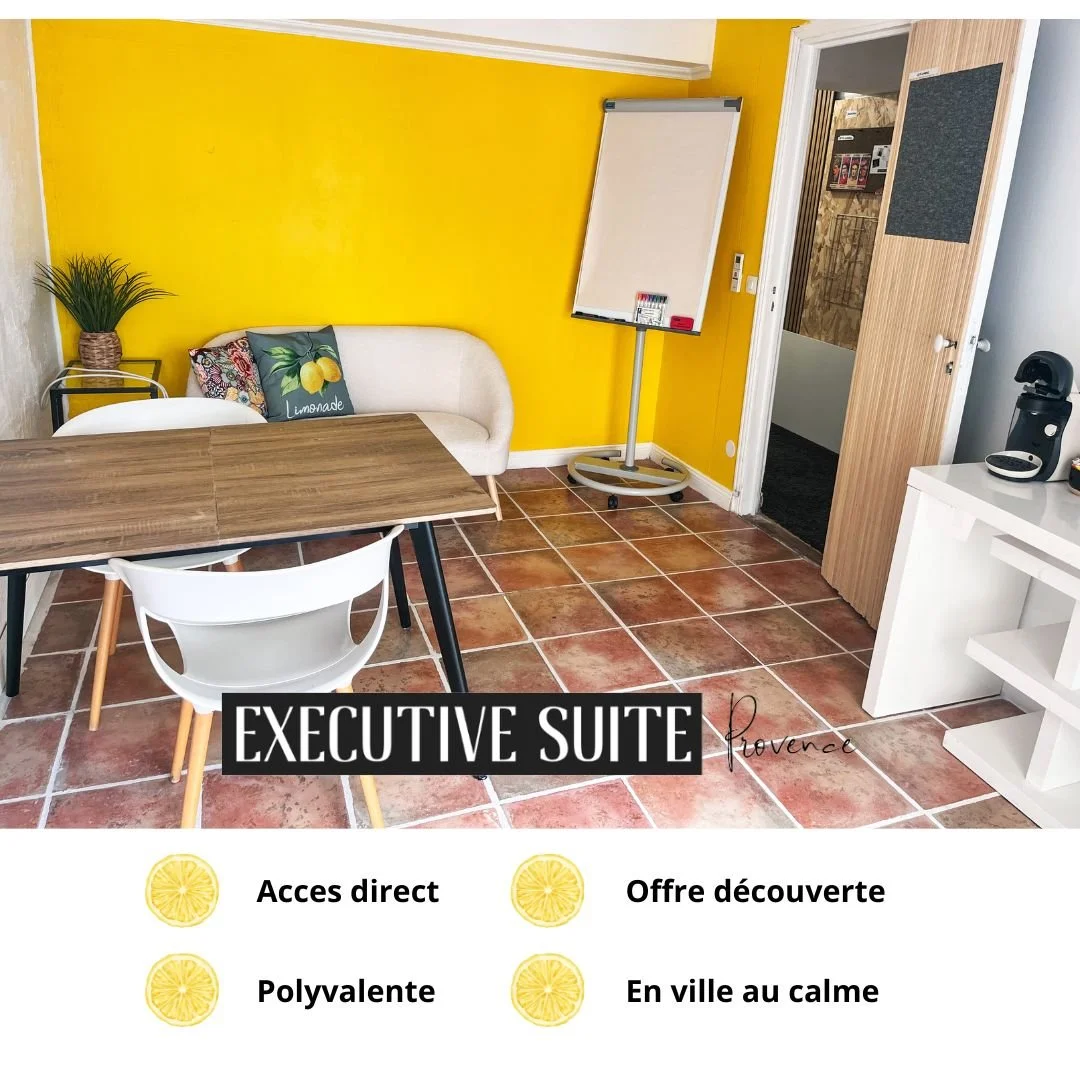 Une salle avec un mur jaune, un canapé blanc avec des coussins, une table en bois, et une porte en bois. Il y a aussi un tableau blanc, une plante dans un pot, une machine à café, et un meuble blanc. Il y a un texte "EXECUTIVE SUITE Provence" en bas