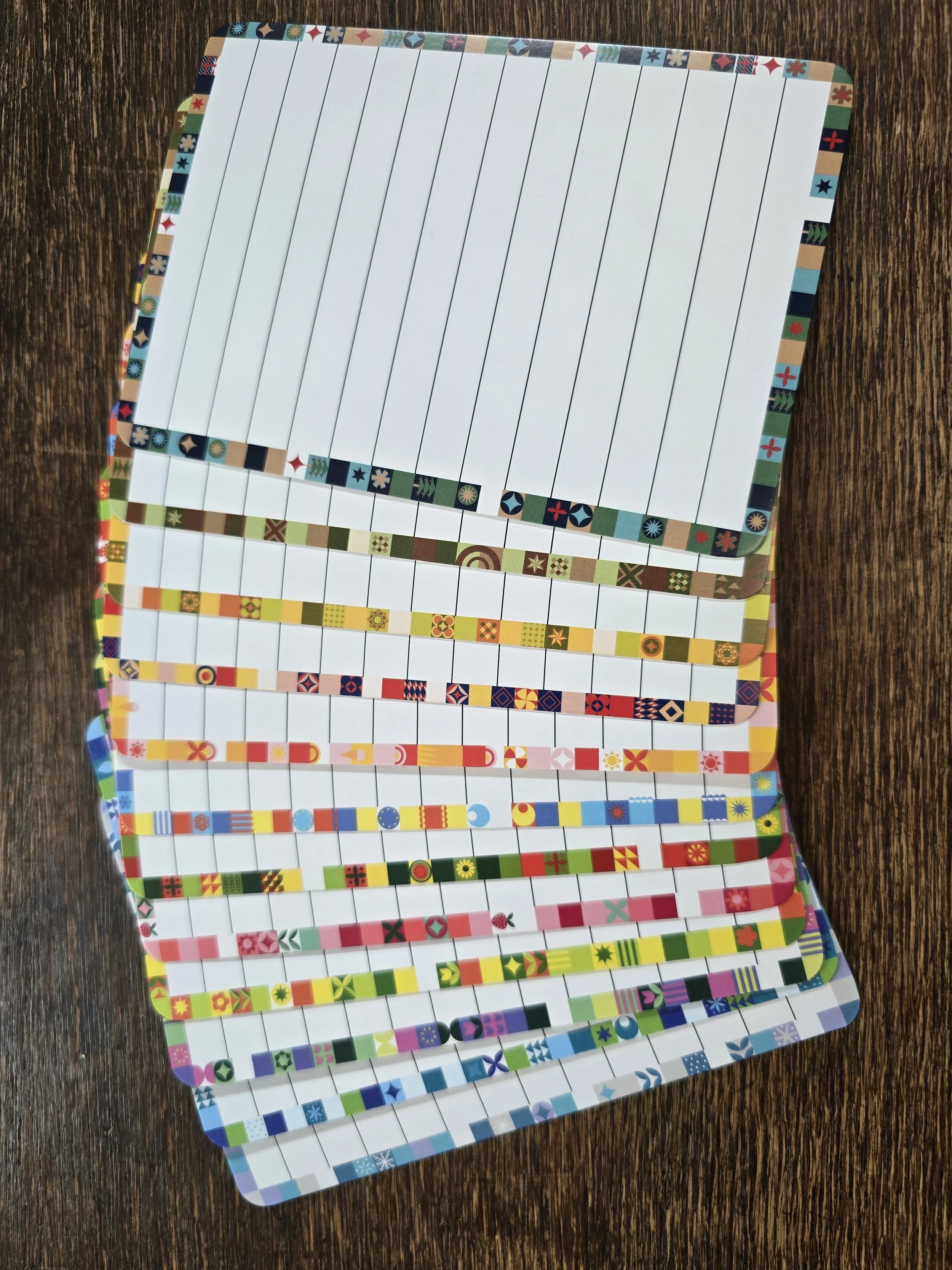 Mehrere verschiende Kanban-Boards mit bunten Muster, auf einem Holztisch.