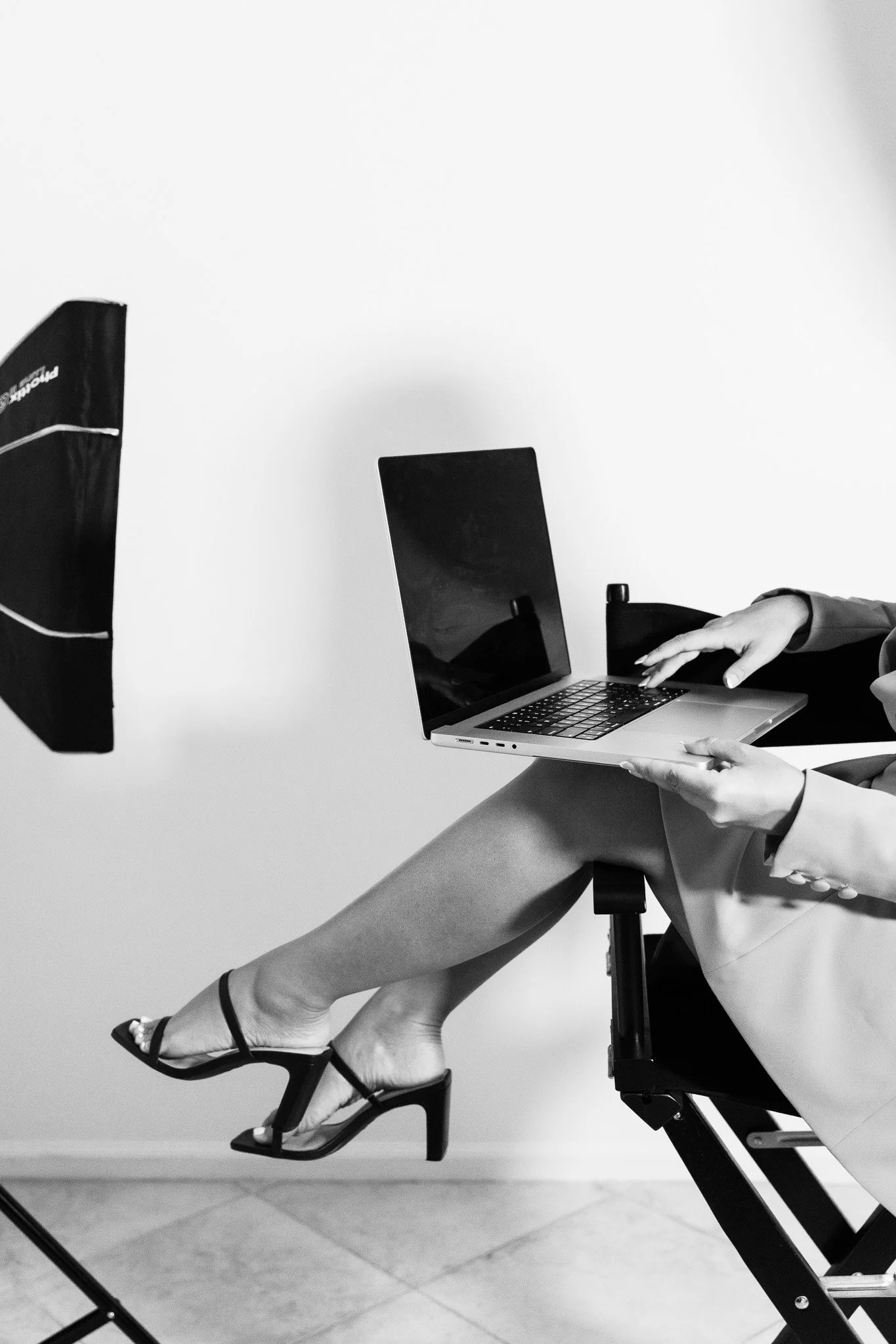 Womans legs hang in the air wearing heels with a laptop on her lap