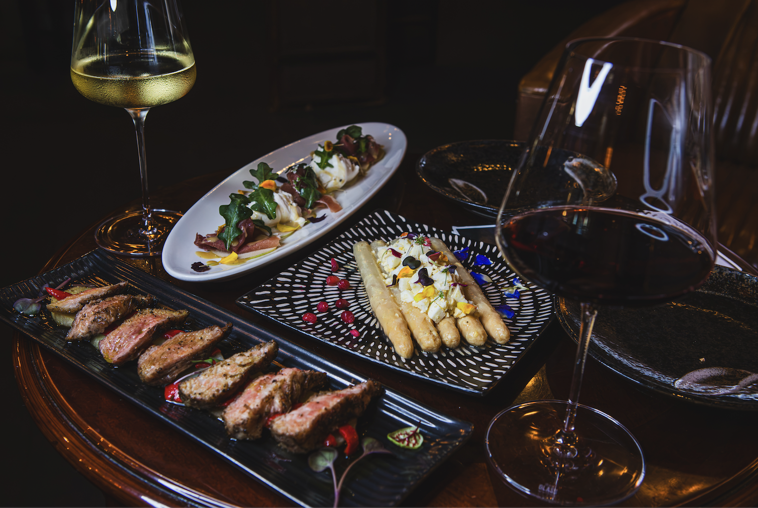 Platos de tapas españolas acompañados de copas de vino tinto y blanco en el Mesón Sommelier.