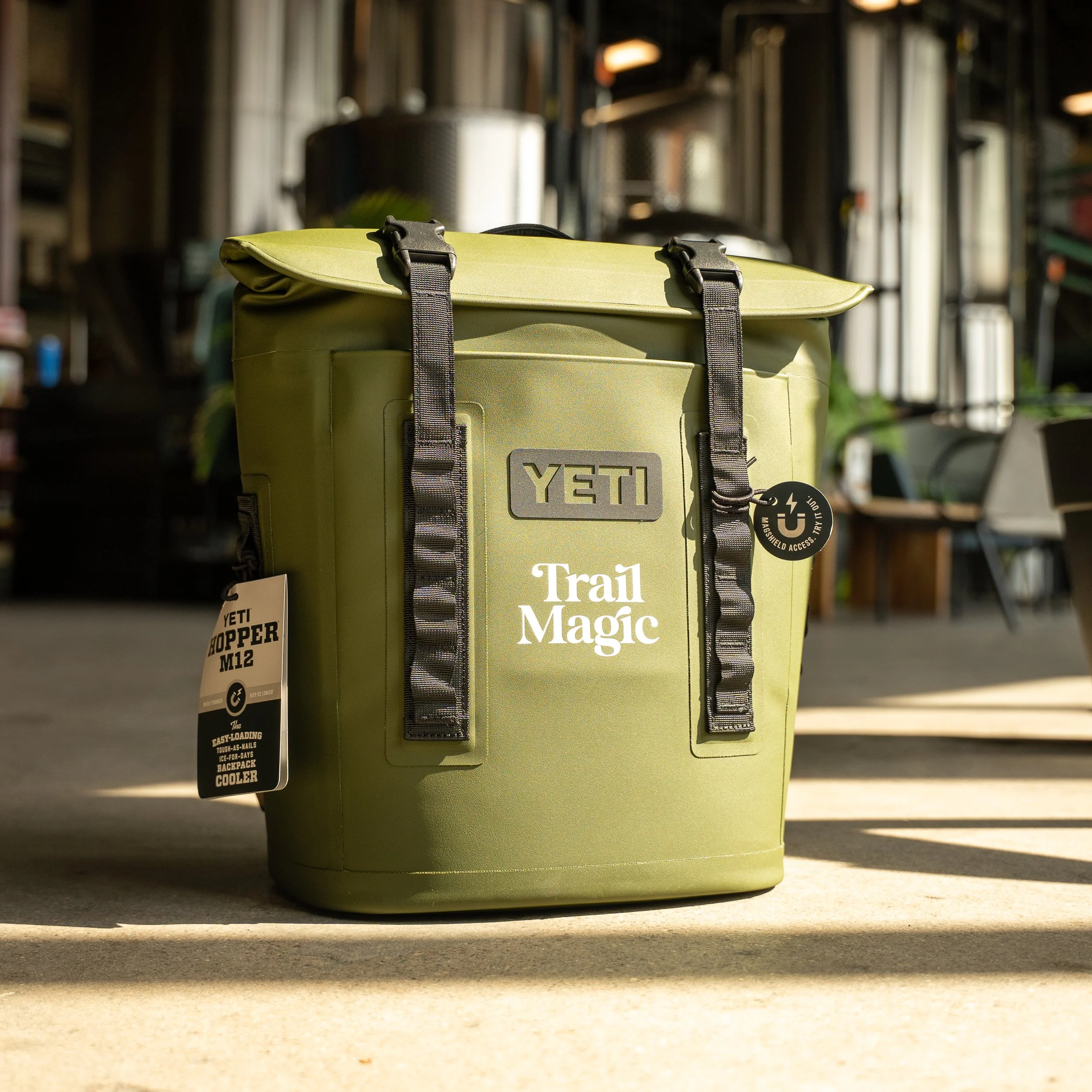 A green YETI Trail Magic cooler with black straps, standing on a concrete floor inside a store or warehouse.