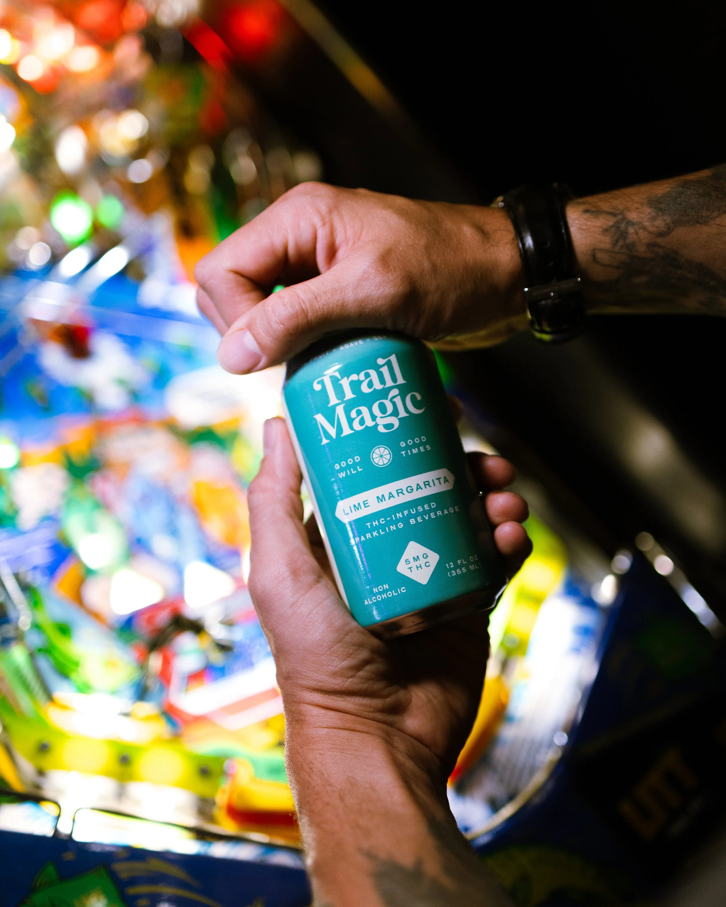Person holding a can labeled 'Trail Magic Lime Margarita THC-Infused Sparkling Beverage' inside a store, with colorful products in the background.