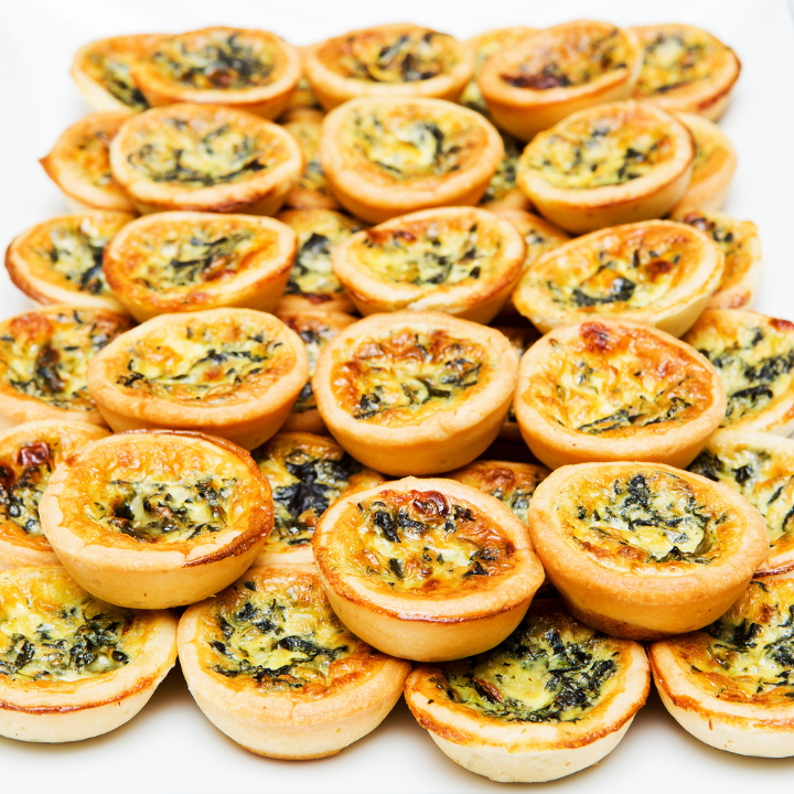 Mini quiches aux épinards et au fromage sur une assiette blanche.