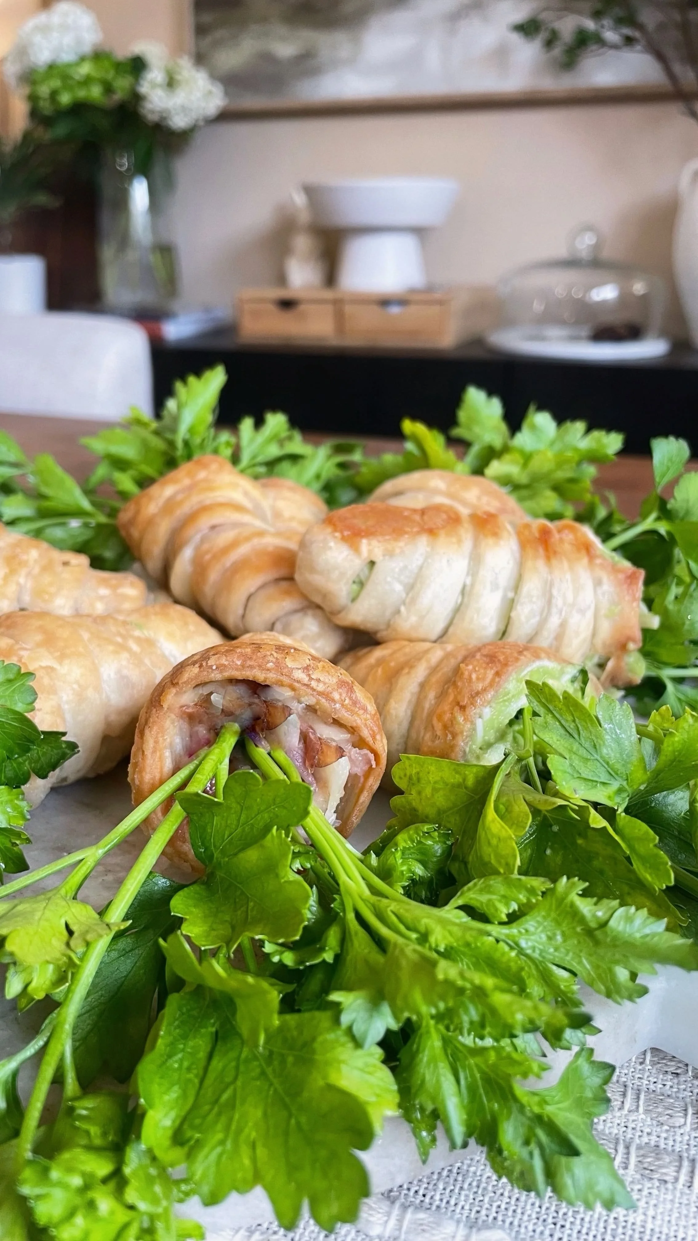 Close-up of a hand holding a puff pastry carrot filled with prosciutto and melted gruyère, showing the flaky layers and savory filling